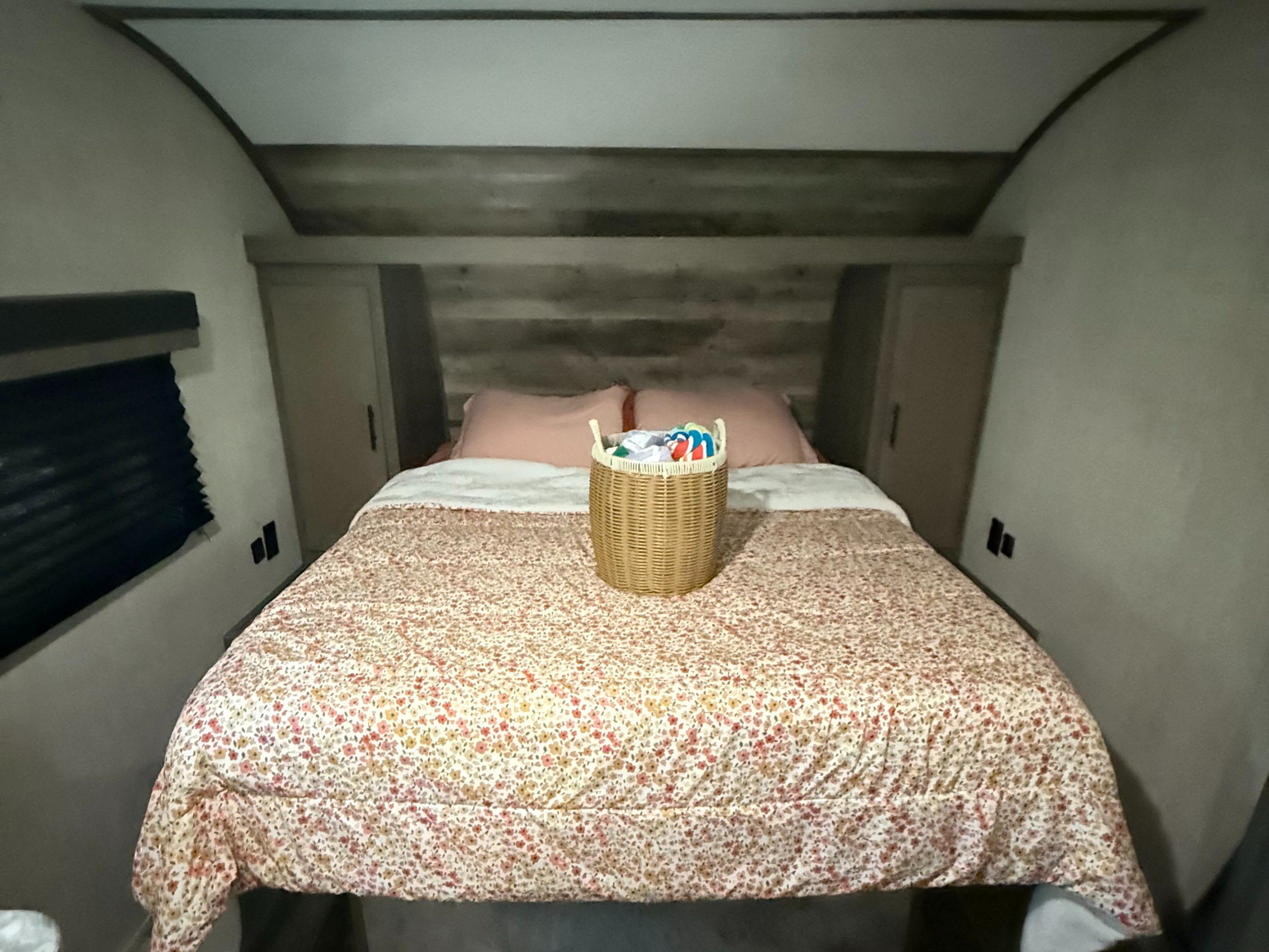 Cozy RV rental bedroom with a floral-patterned queen bed, pink pillows, built-in storage, and wood-look flooring.. Gulf Stream Ameri-Lite 2022