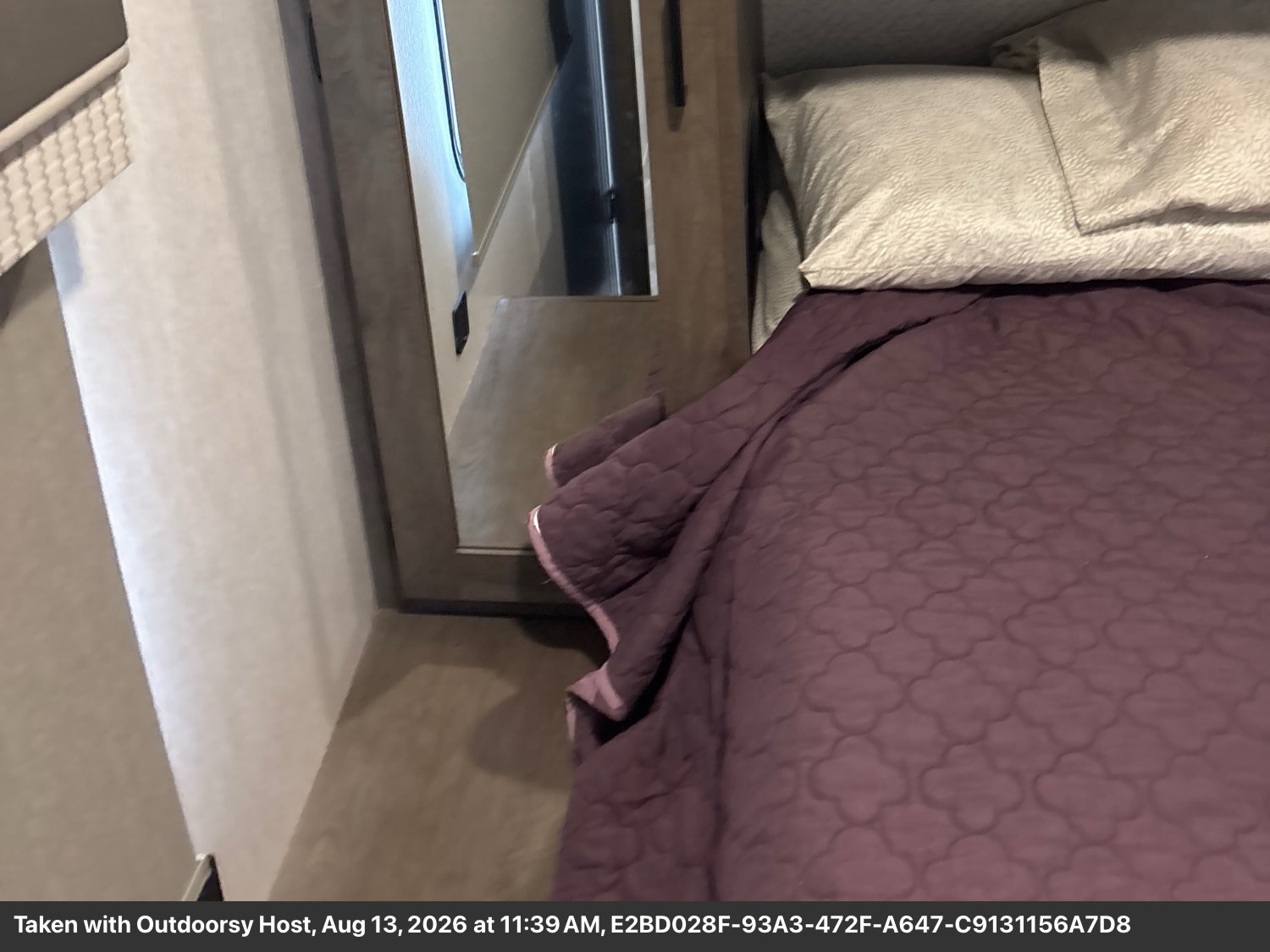 Comfortable RV rental bedroom featuring a purple quilted bed, pillows, and a nearby mirror for a cozy interior.. Forest River Salem 2022