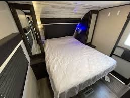 Inside an RV rental! Comfortable travel trailer bedroom features a queen bed, nightstands, and a full-length mirror.. Jayco White Hawk 2021