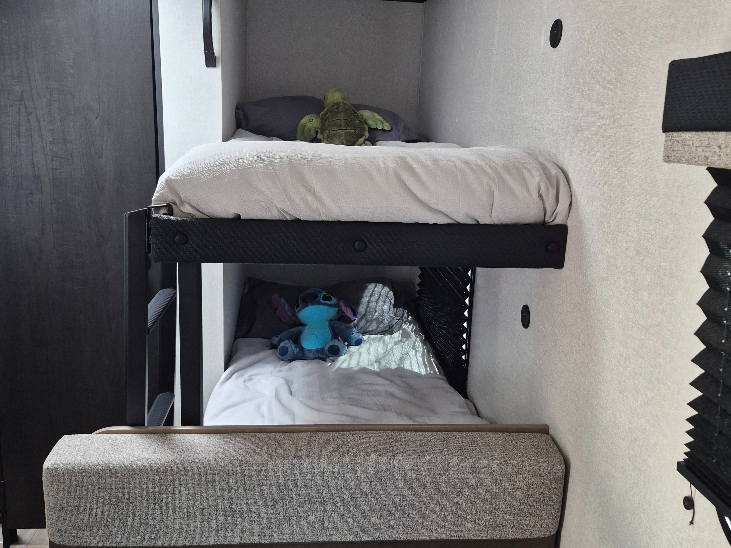 Cozy RV rental bunk beds, complete with stuffed turtle and Stitch, offer comfortable sleeping for family camping adventures.. Open Range Colt 17BH 2026