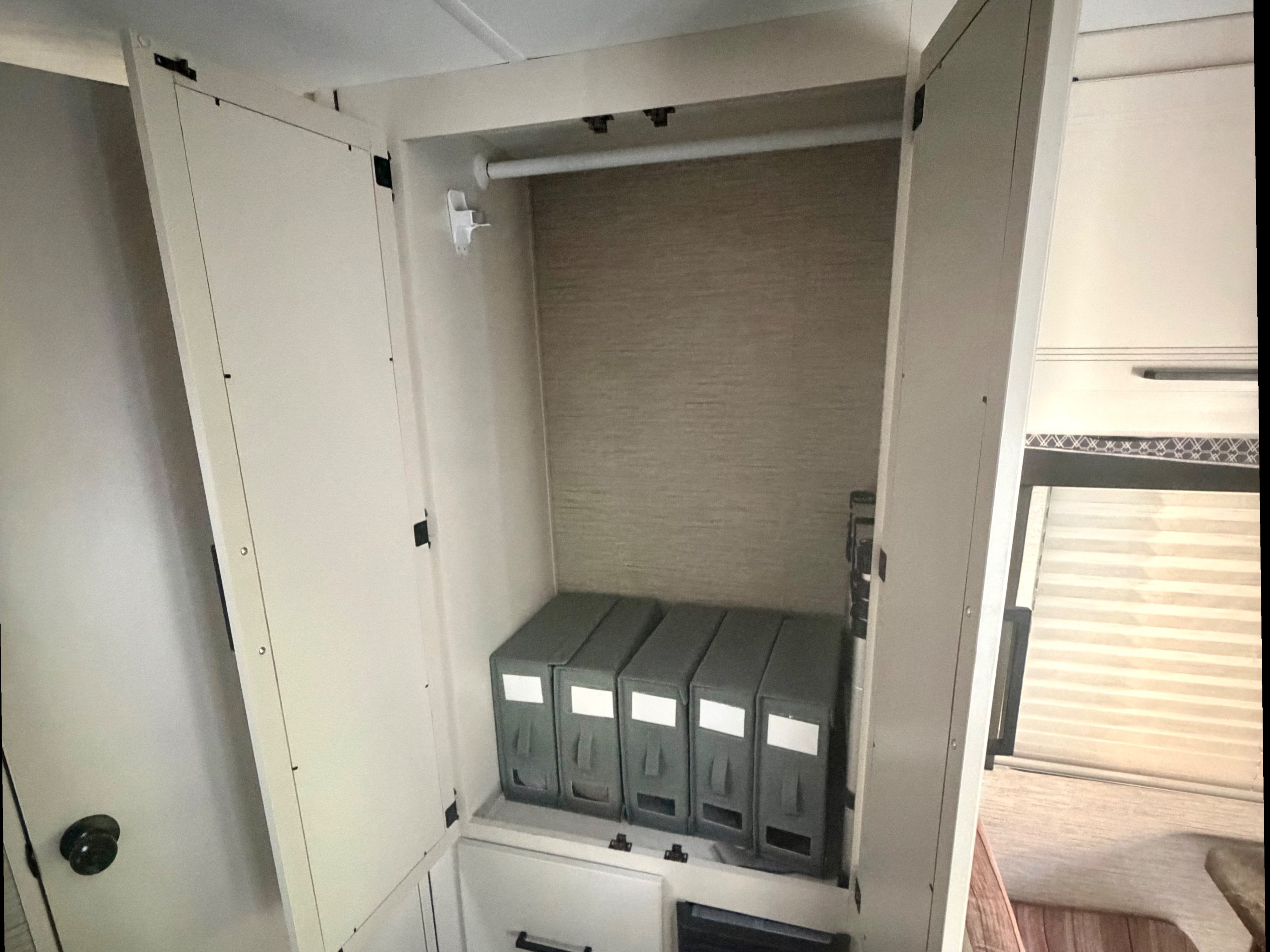 RV rental closet, perfect for organized travel. Features a hanging rod, multiple storage boxes, and lower cabinets.. Thor Four Winds 2023