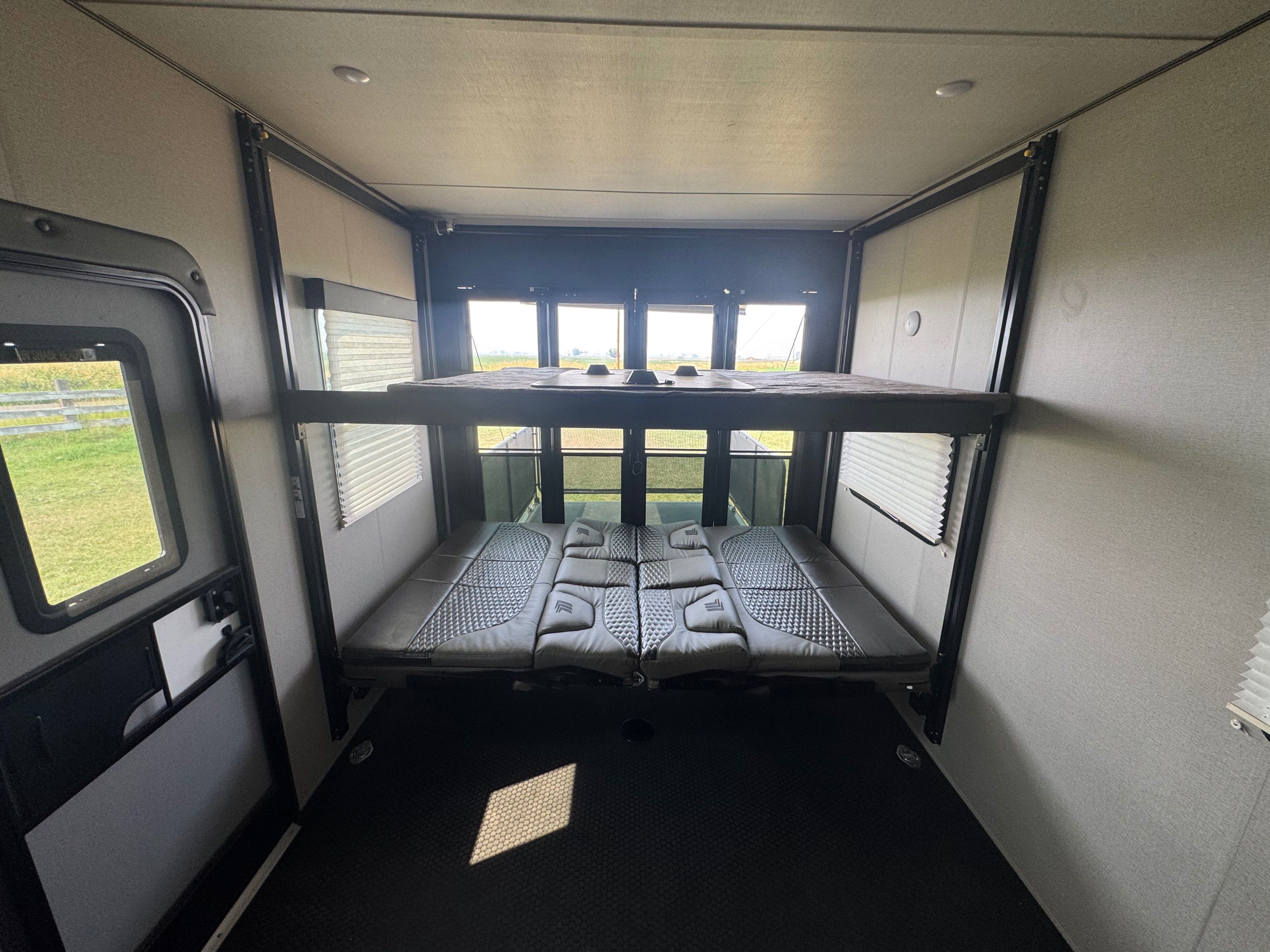 Inside an RV rental: a modern toy hauler interior with adjustable bunk beds and a scenic view from the rear windows.. Grand Design Momentum 2022