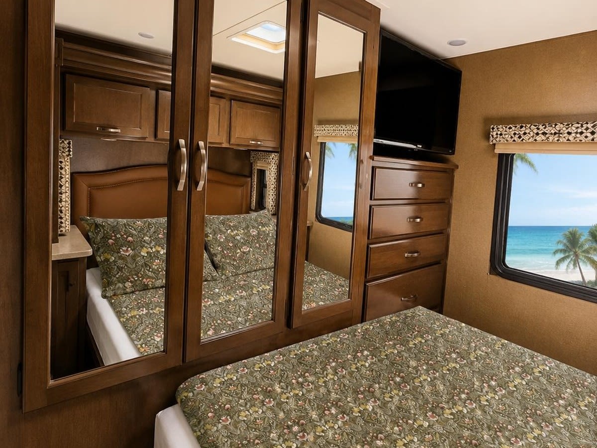 RV rental bedroom: comfortable bed, mirrored closet, TV, and stunning beach and ocean view window.. Thor Freedom Elite 2018