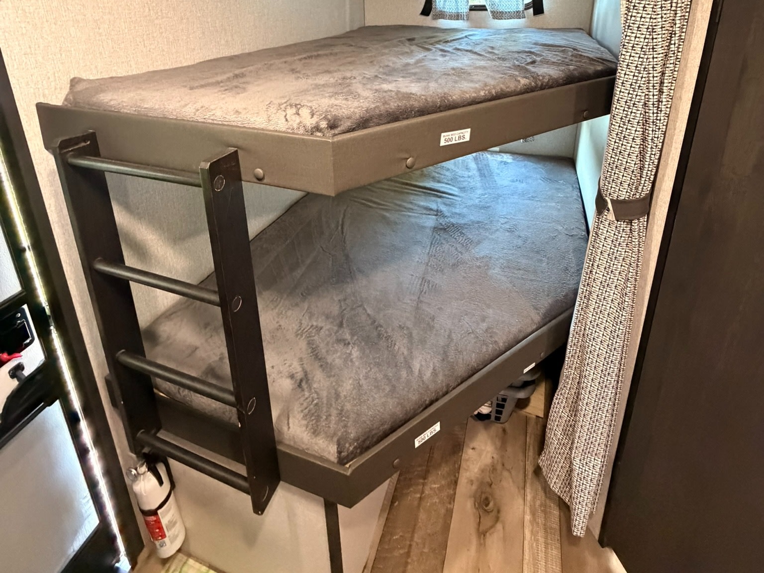 Cozy bunk beds in an RV rental, complete with a ladder and visible fire extinguisher for safety. Perfect for family adventures.. KZ Connect 2022