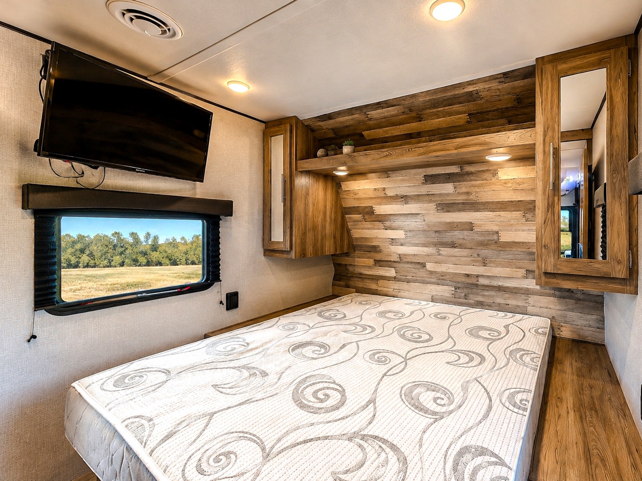 Cozy RV rental bedroom with comfortable bed, wood accent wall, TV, and scenic window view, perfect for travel.. Zinger 333DB 2022