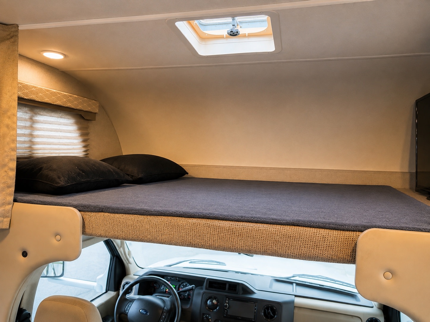 This RV rental's cozy overhead bunk bed, complete with a skylight and pillows, is situated above the driver's cabin.. Thor Freedom Elite 2020
