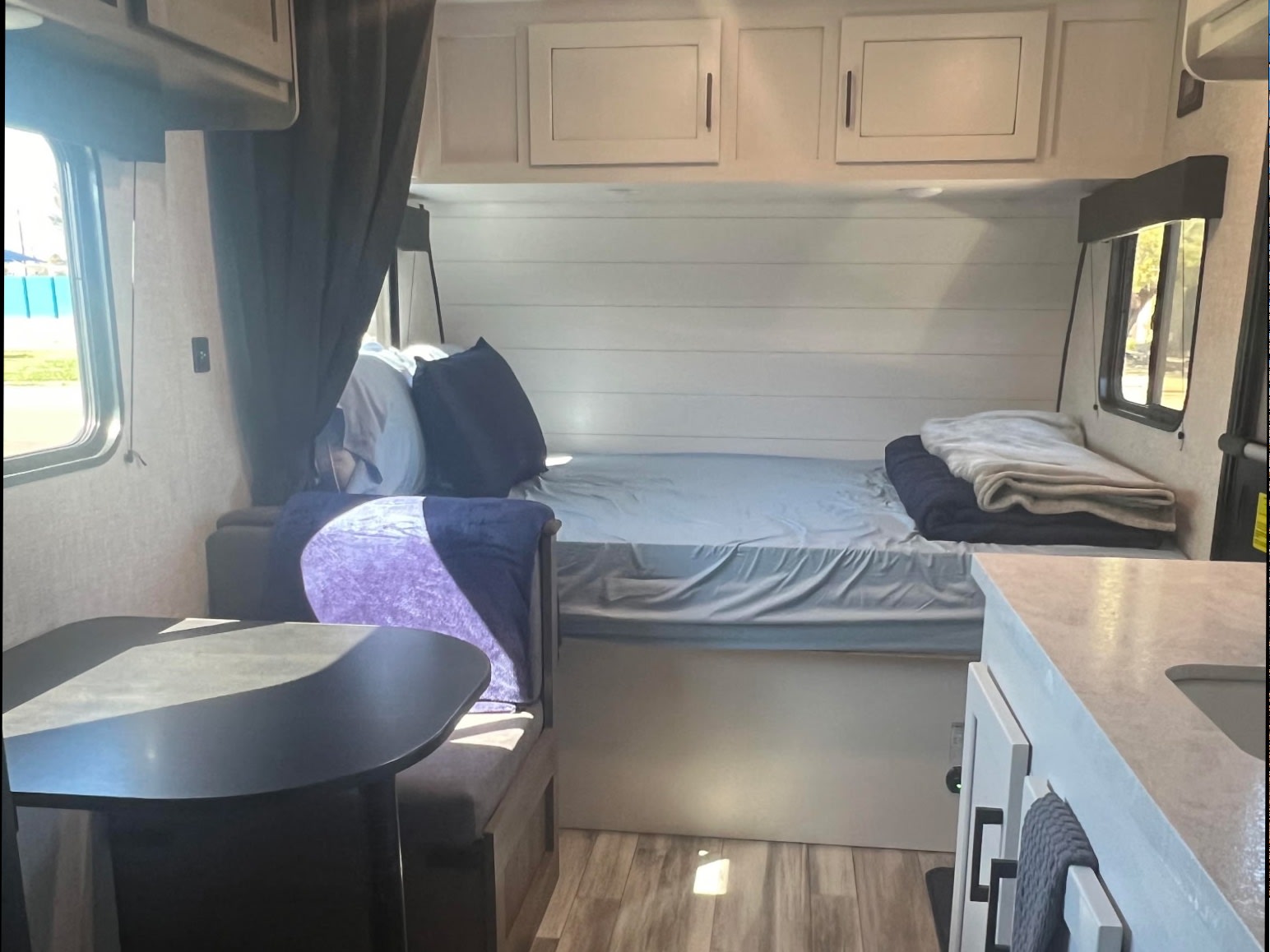 Cozy RV rental interior featuring a bed, dining area with table, and a compact kitchen counter.. Jayco Jay Flight SLX Baja Edition 2024