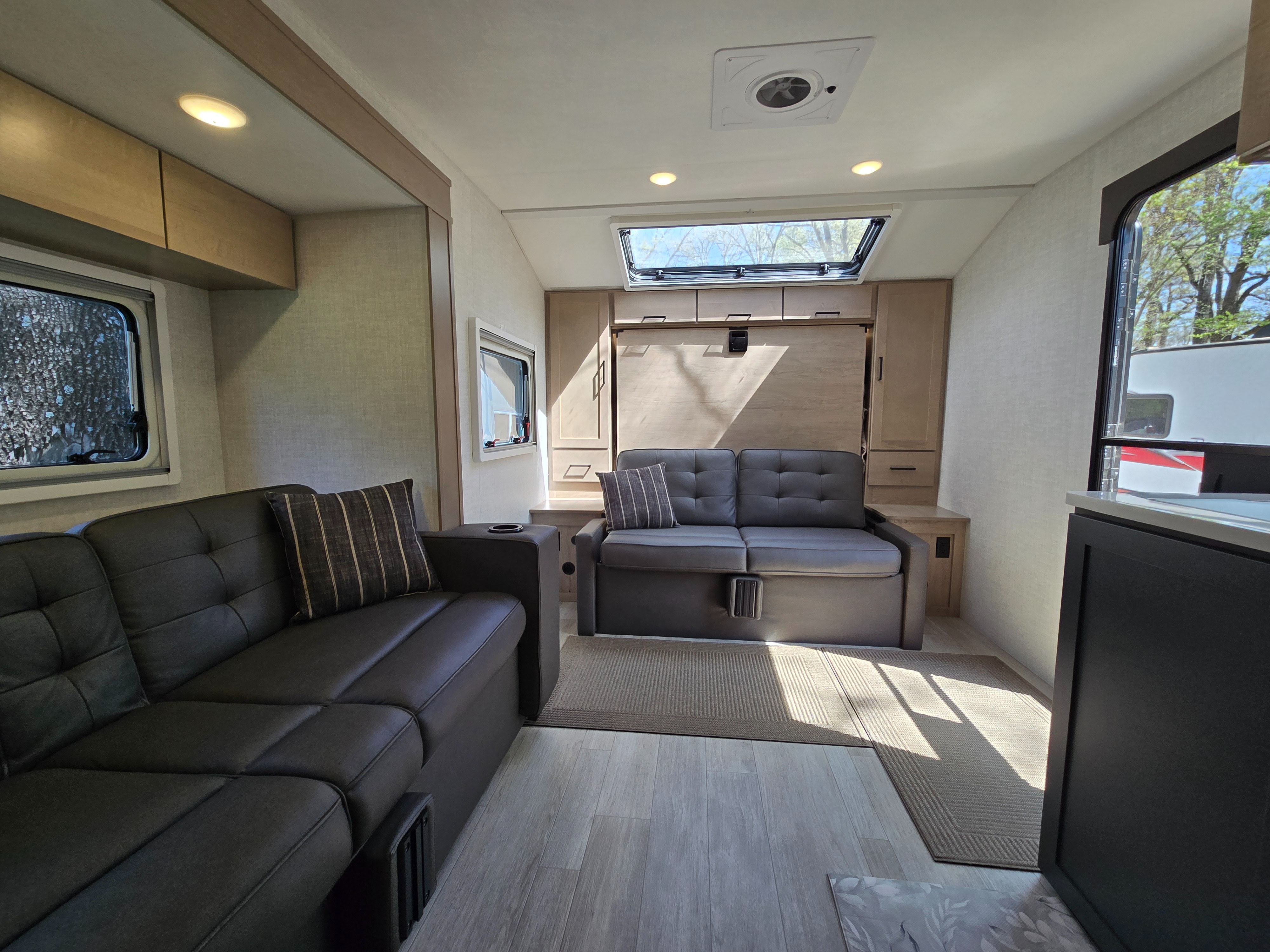 Modern RV rental living area with comfy sofas, sleek finishes, a bright skylight, and wood-look flooring.. Ember OVERLAND / 221MSL 2026