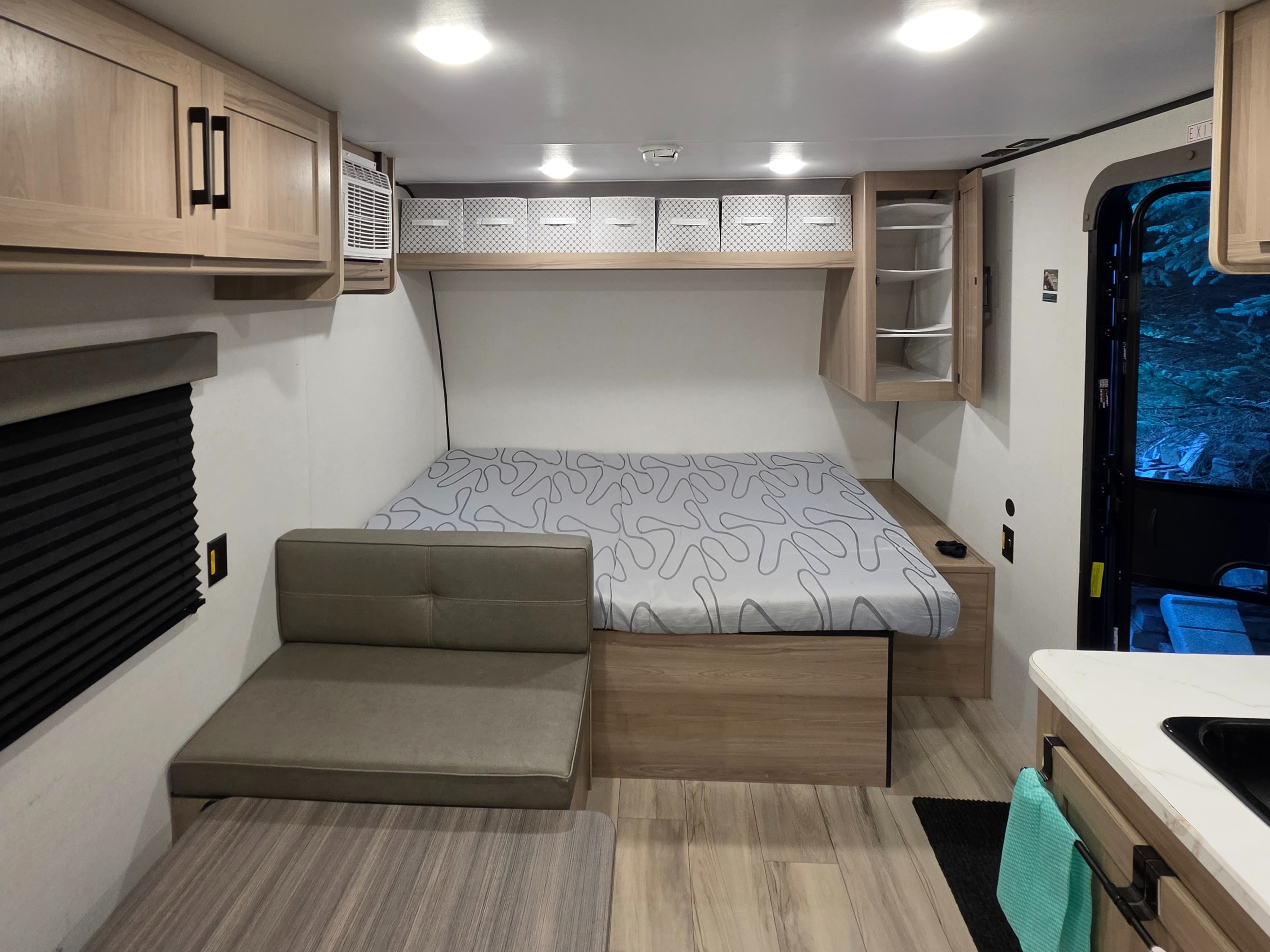 Cozy rv rental interior with a bed, dinette, overhead cabinets, and kitchenette corner for a comfortable travel experience.. Keystone RV Coleman 2025
