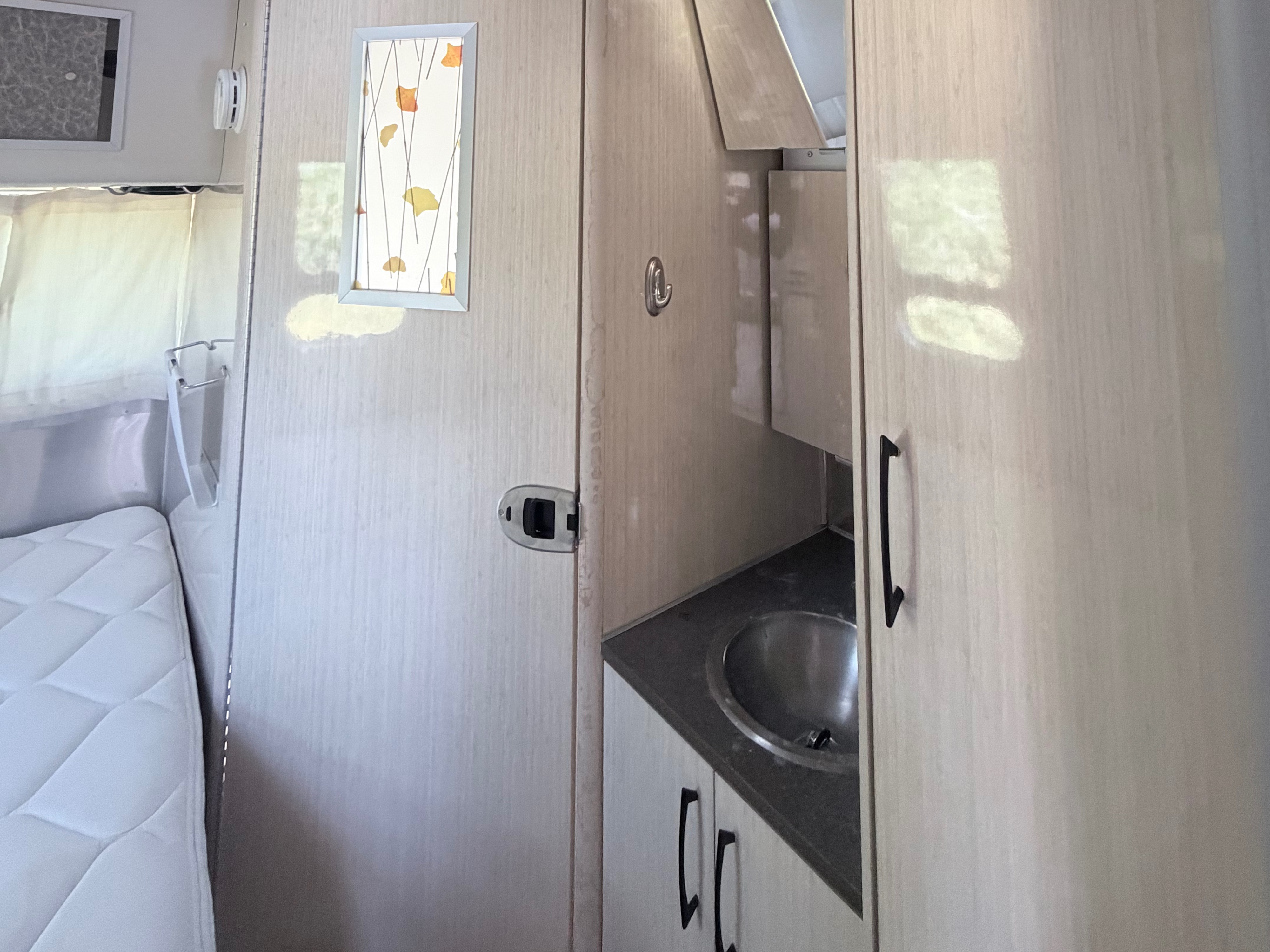 RV rental: Clean, modern interior. Features a comfortable bed, compact kitchenette sink, and storage cabinets.. Airstream International 2015