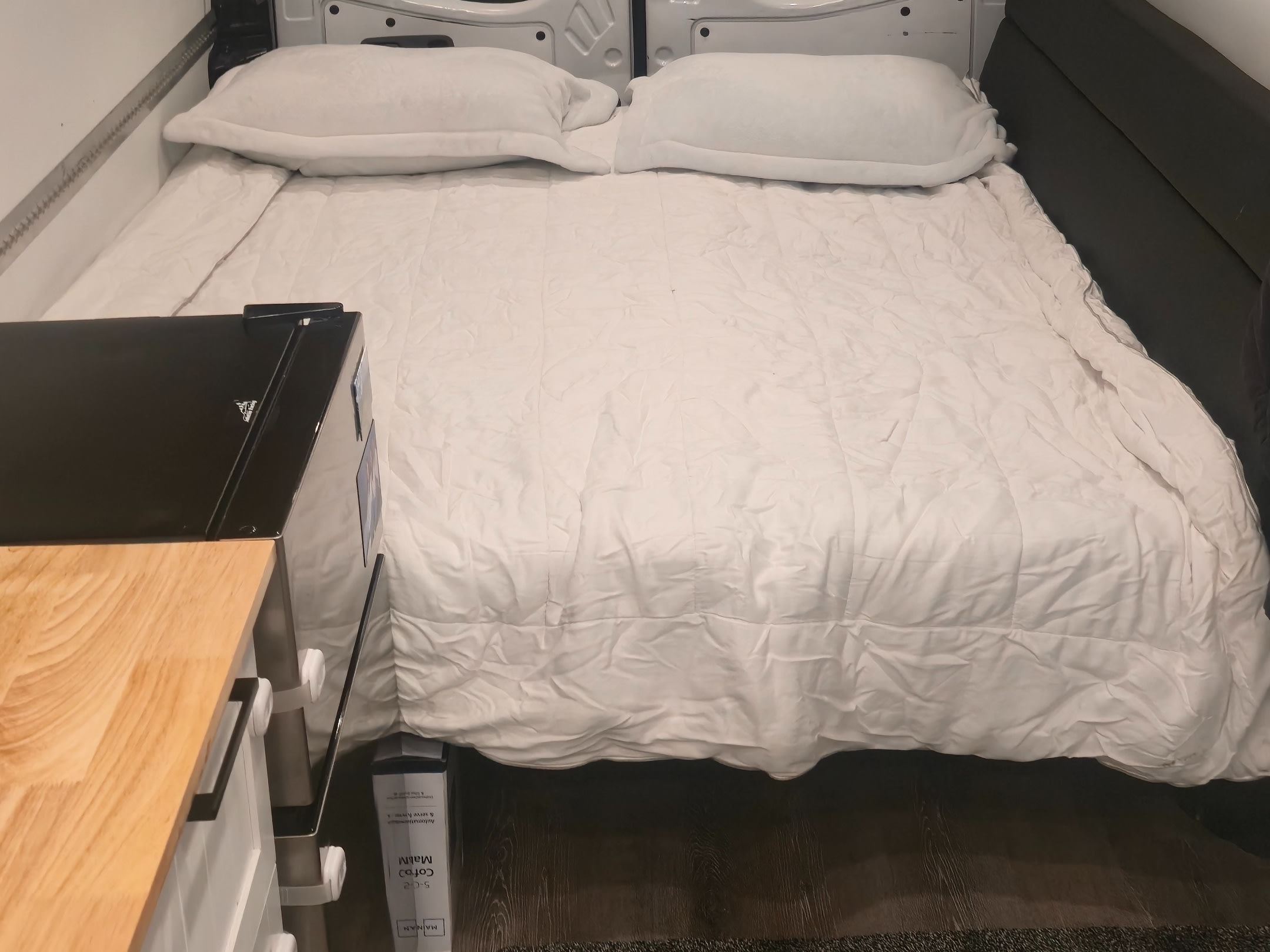 This RV rental offers a comfortable sleeping area with white pillows and bedding, next to a compact kitchen counter.. Freightliner Sprinter 2016
