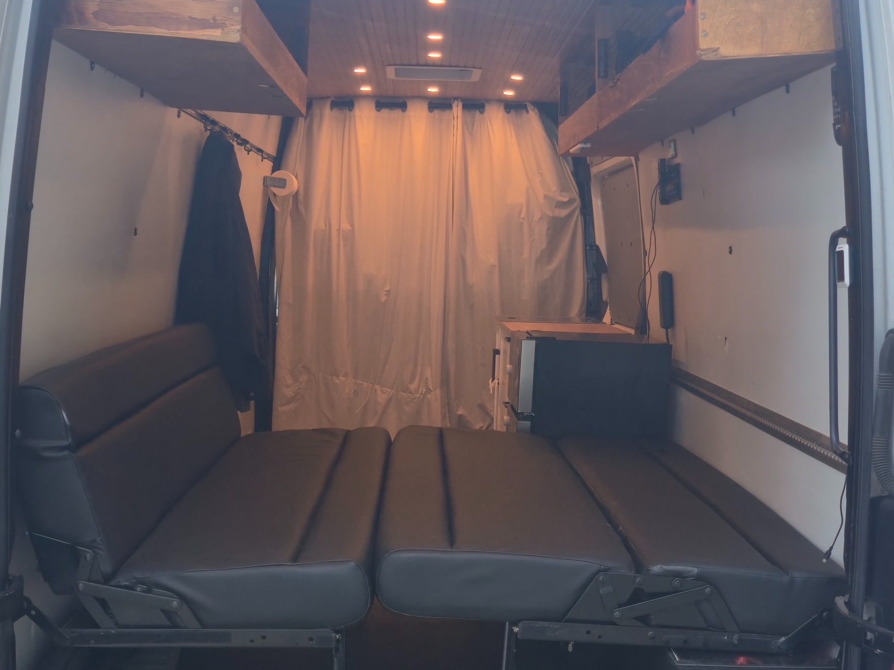 RV rental camper van interior: convertible bed, wooden shelves, privacy curtains, and LED lights for a cozy setup.. Freightliner Sprinter 2016