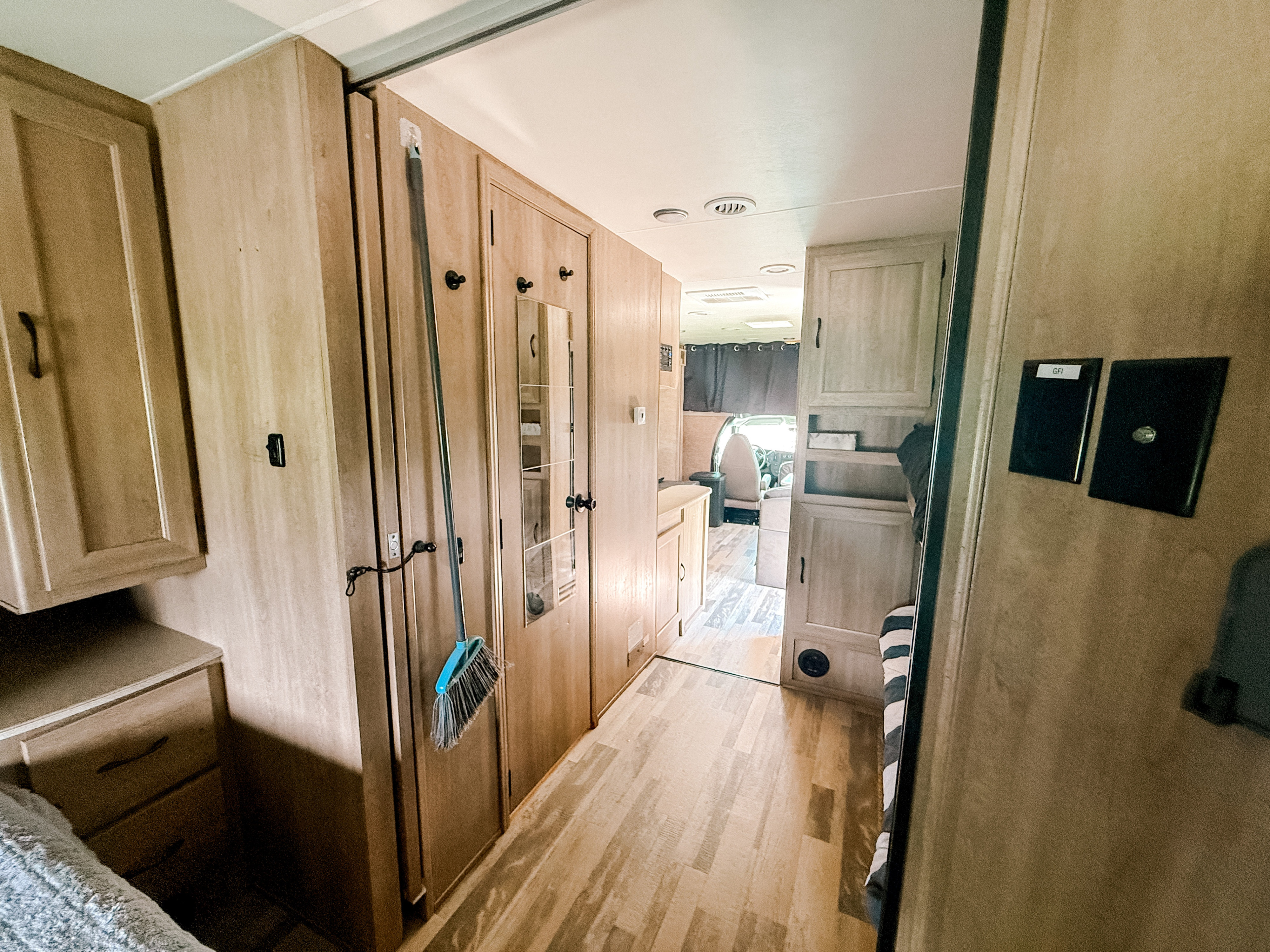 RV rental interior: A bright hallway with light wood cabinets, broom, mirror, and flooring, leading to living and sleeping areas.. Coachmen Freelander 2015