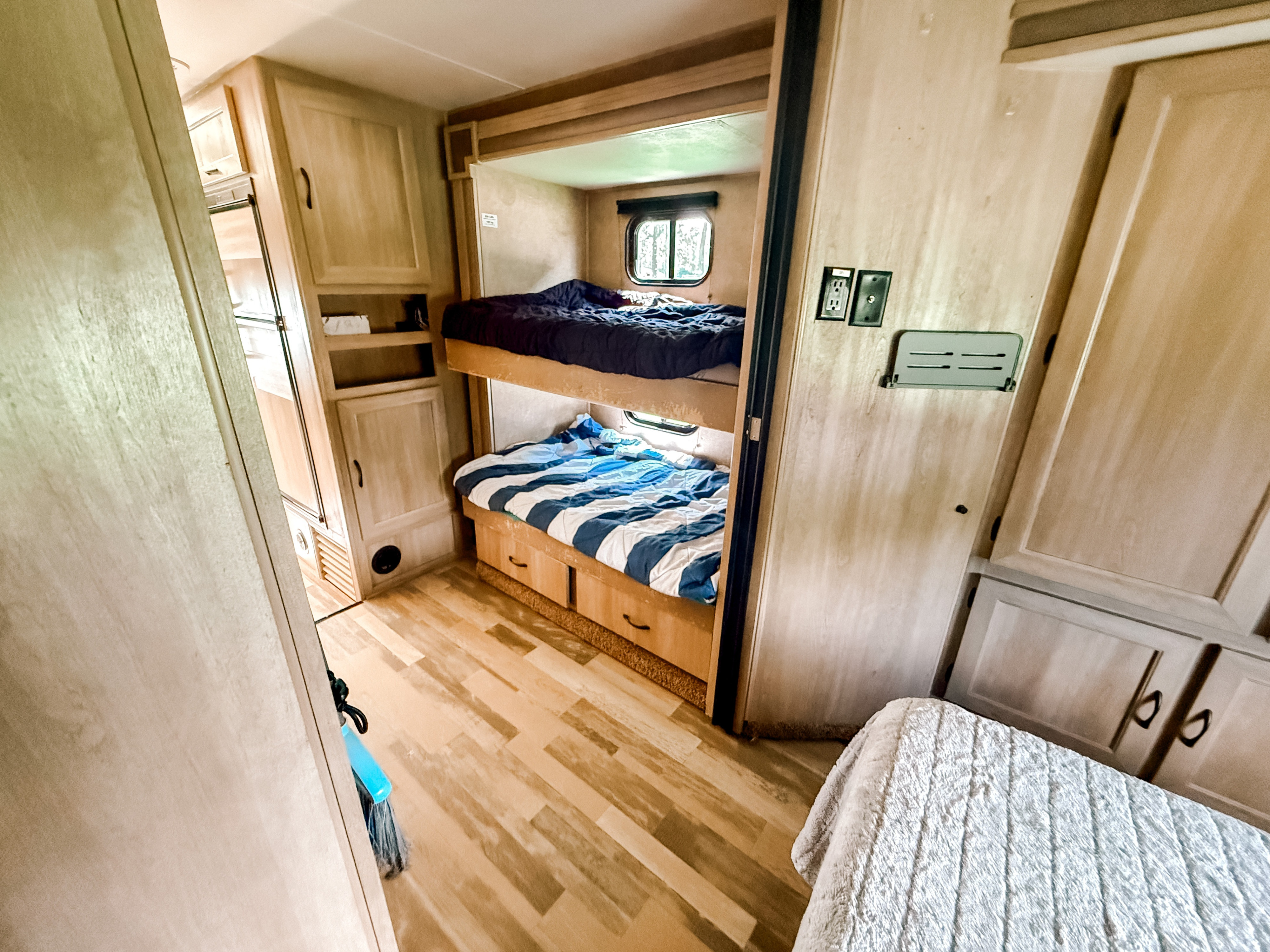 This RV rental features a bright interior with two bunk beds, a window, storage cabinets, and a partial view of another bed.. Coachmen Freelander 2015