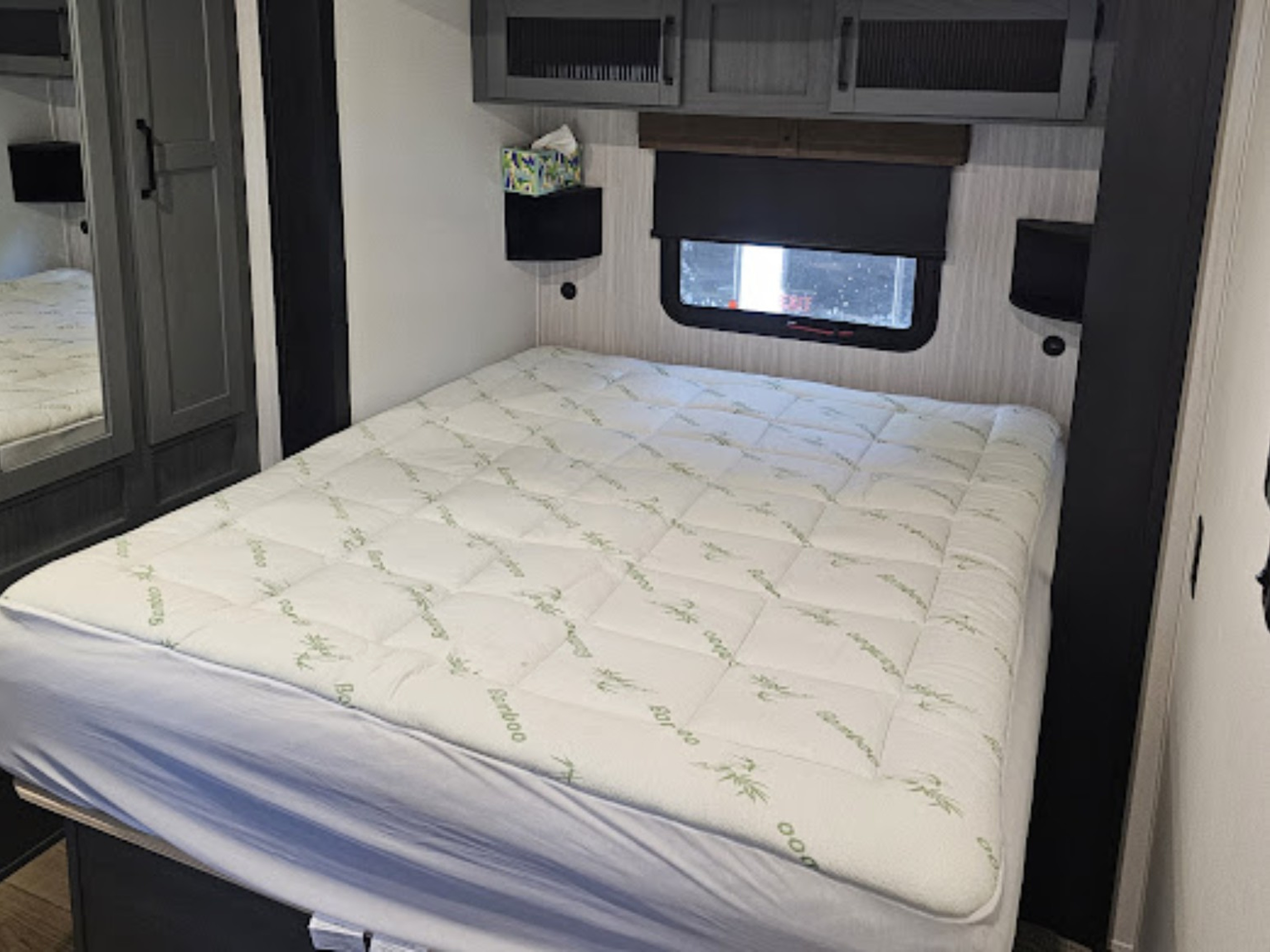 RV rental bedroom showing a cozy bed with a bamboo mattress topper, window, and storage cabinets for comfort.. Forest River Palomino Puma 2026