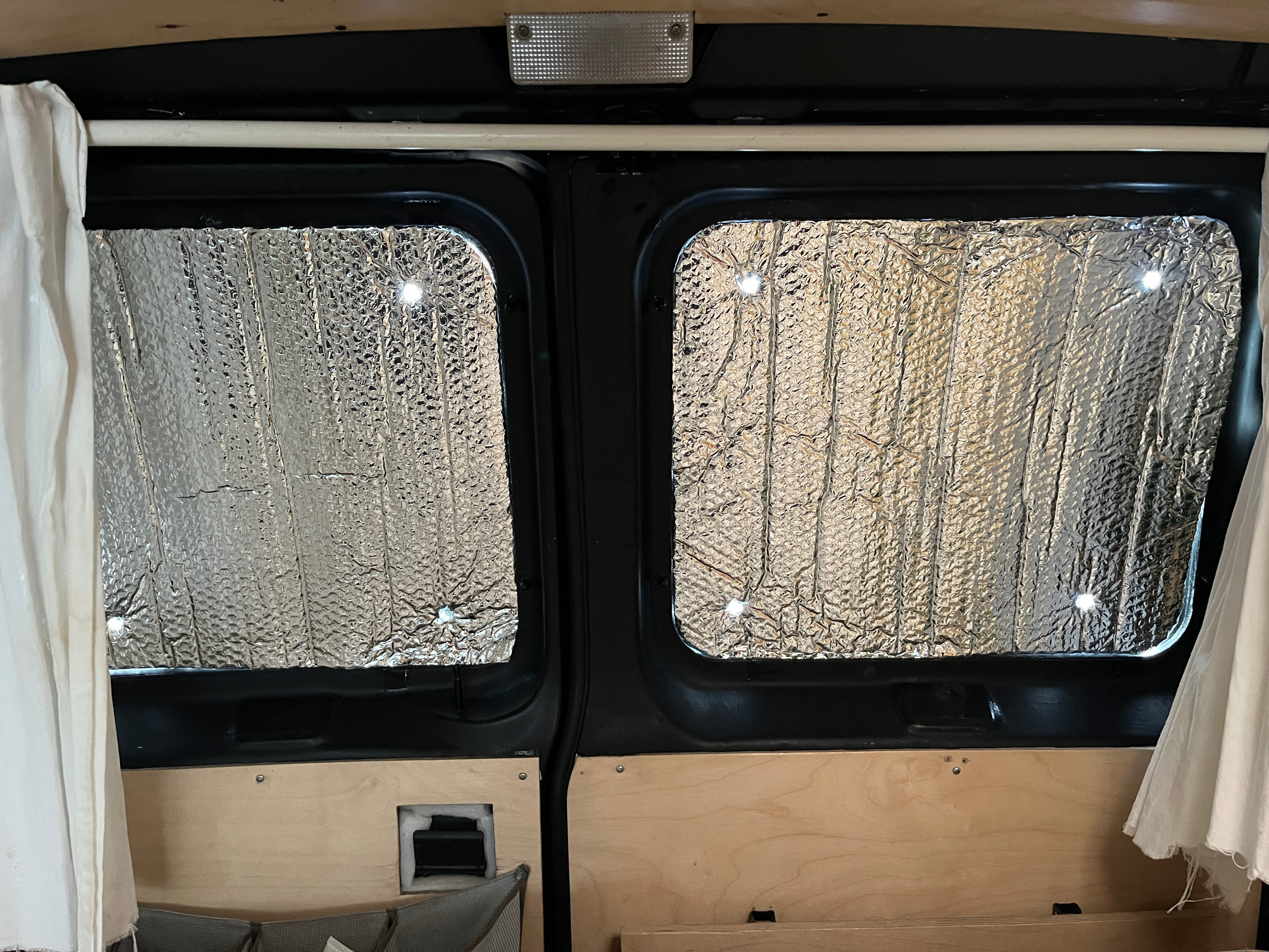 View inside an RV rental camper van: insulated windows for privacy and temperature control, custom wood panels, and curtains.. Ford E250 Eagle Camper 2005