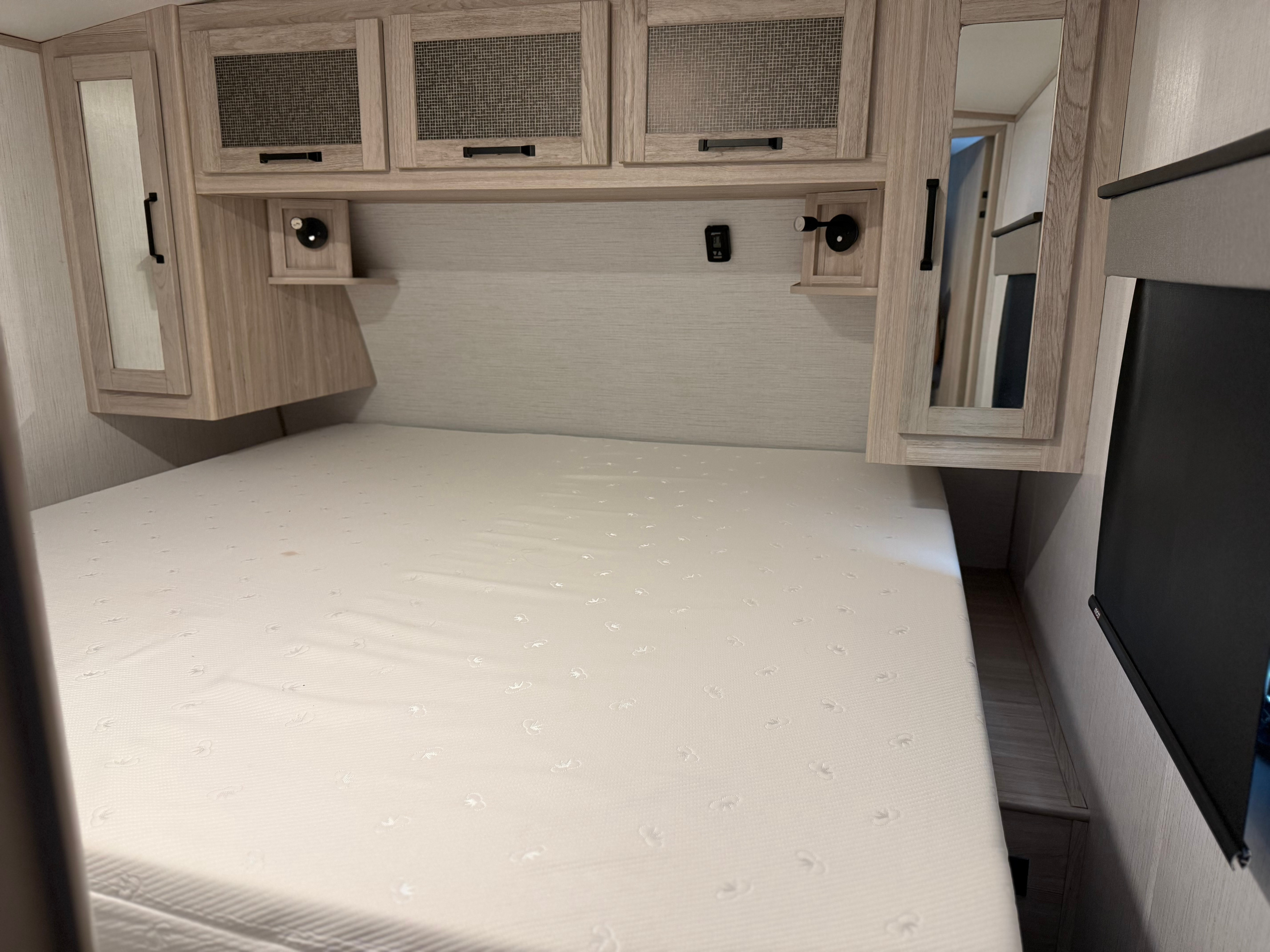 RV rental interior: Clean bedroom with a white mattress, modern overhead cabinets, and built-in lighting beside the bed.. Twilight RVS Signature 2022