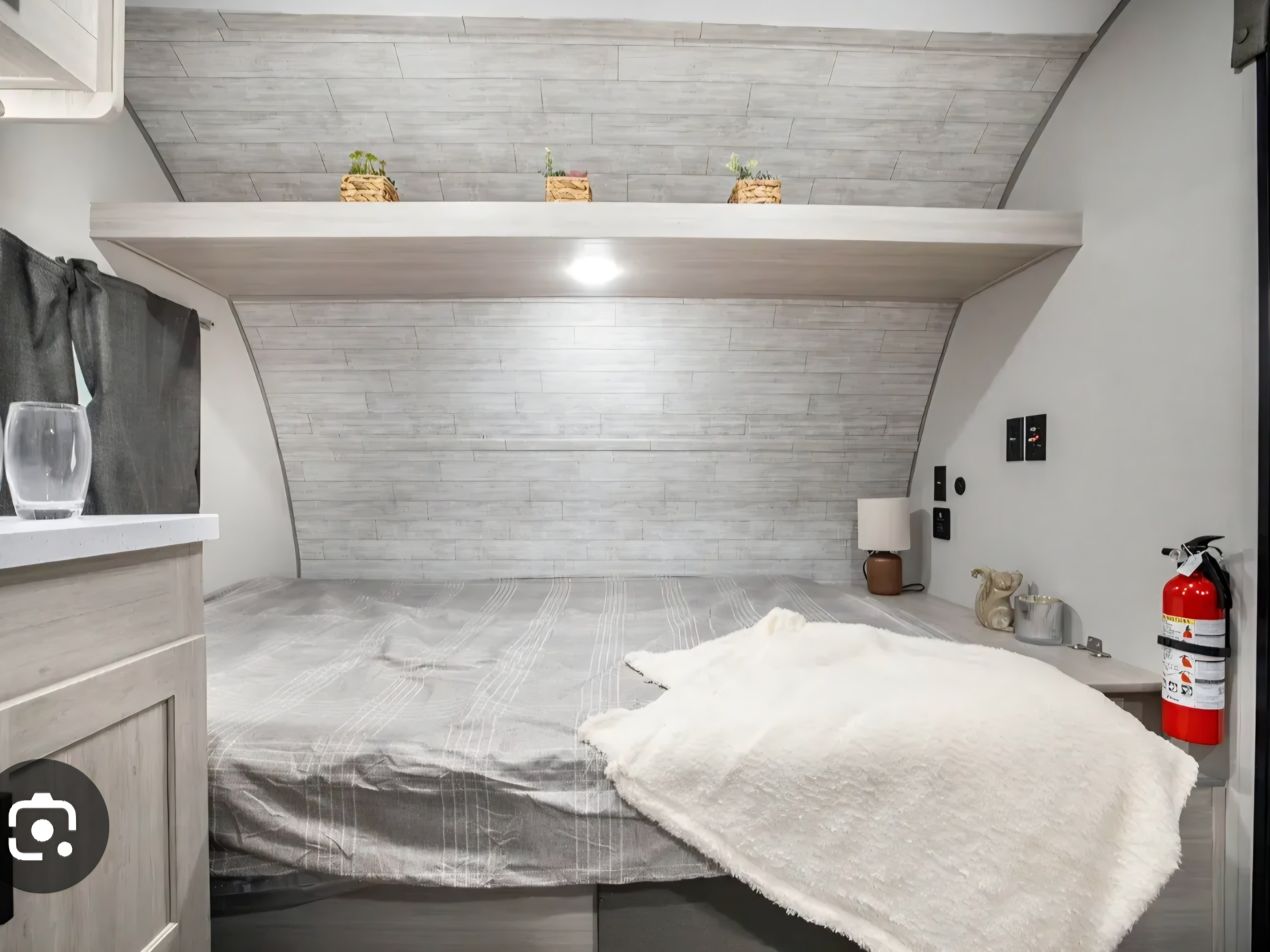 Cozy RV rental bedroom with a comfy bed, overhead shelf decor, and a visible fire extinguisher for safety.. Forest River Aurora Aurora Light 2026