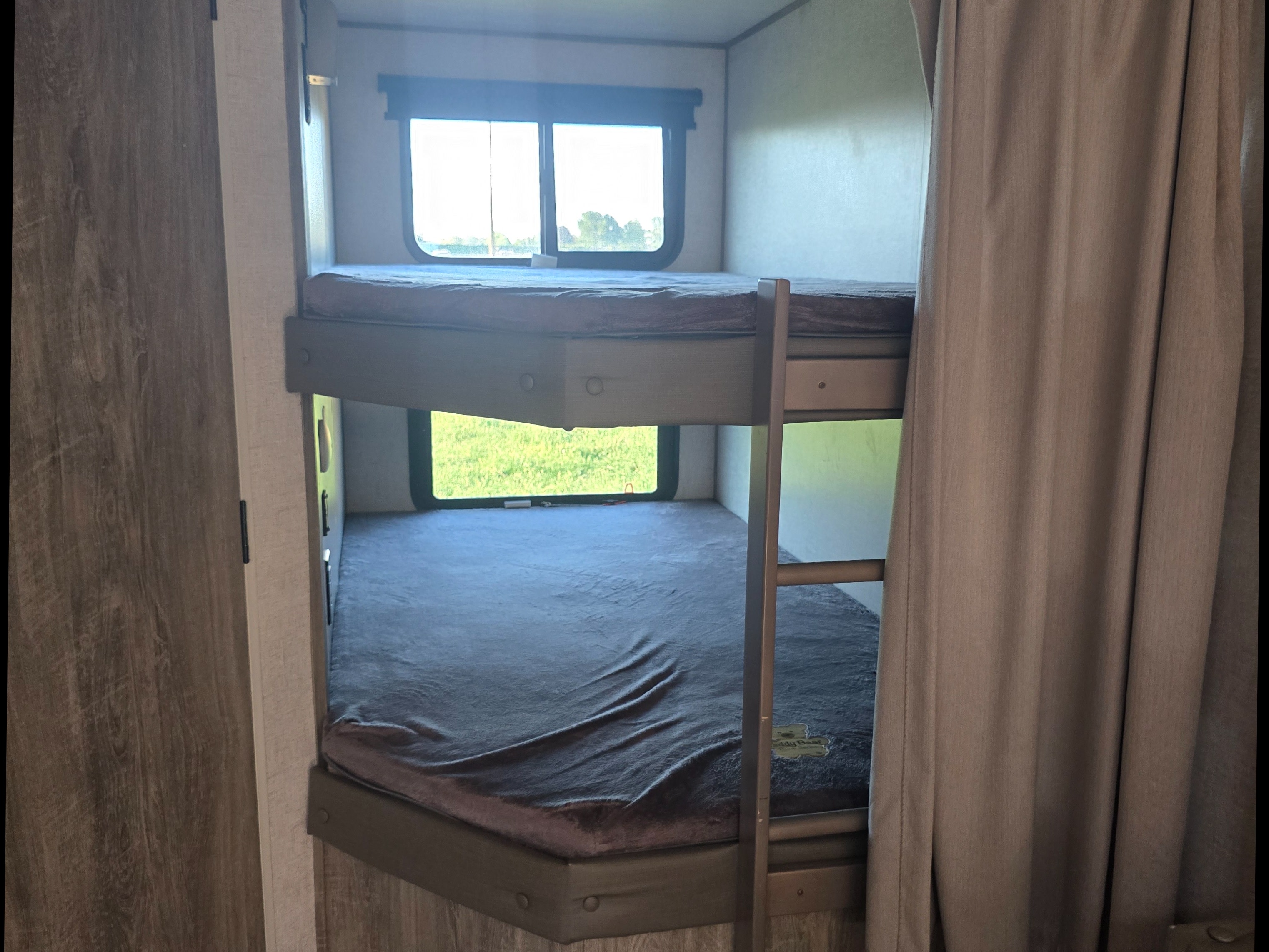 RV rental bunk beds: a cozy sleeping area with windows overlooking a sunny green landscape, perfect for family camping.. Forest River Salem Hemisphere HL 2021
