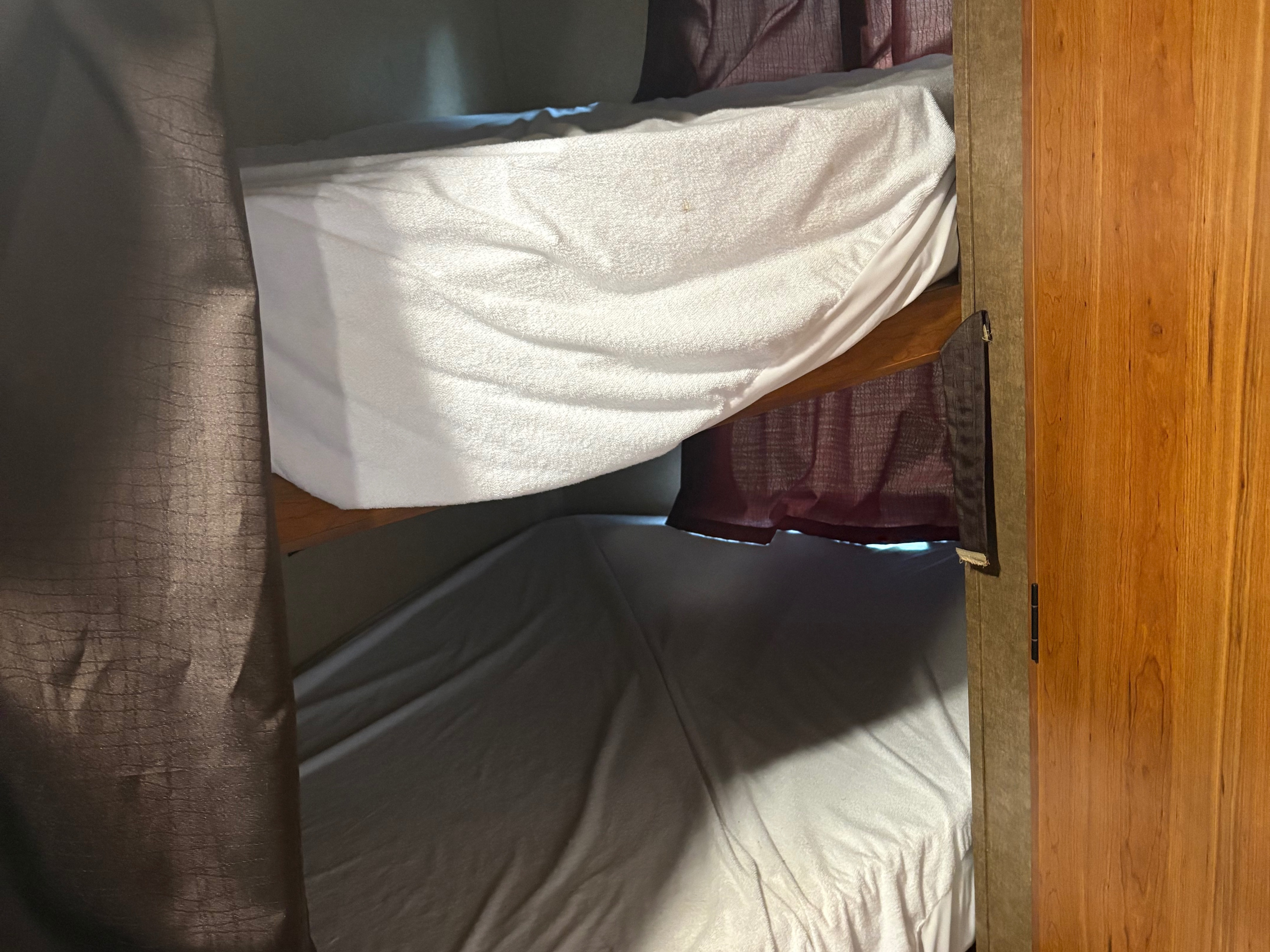 Inside an rv rental: stacked bunk beds with white & grey bedding, framed by dark and burgundy privacy curtains.. Starcraft AR-One Maxx 2016