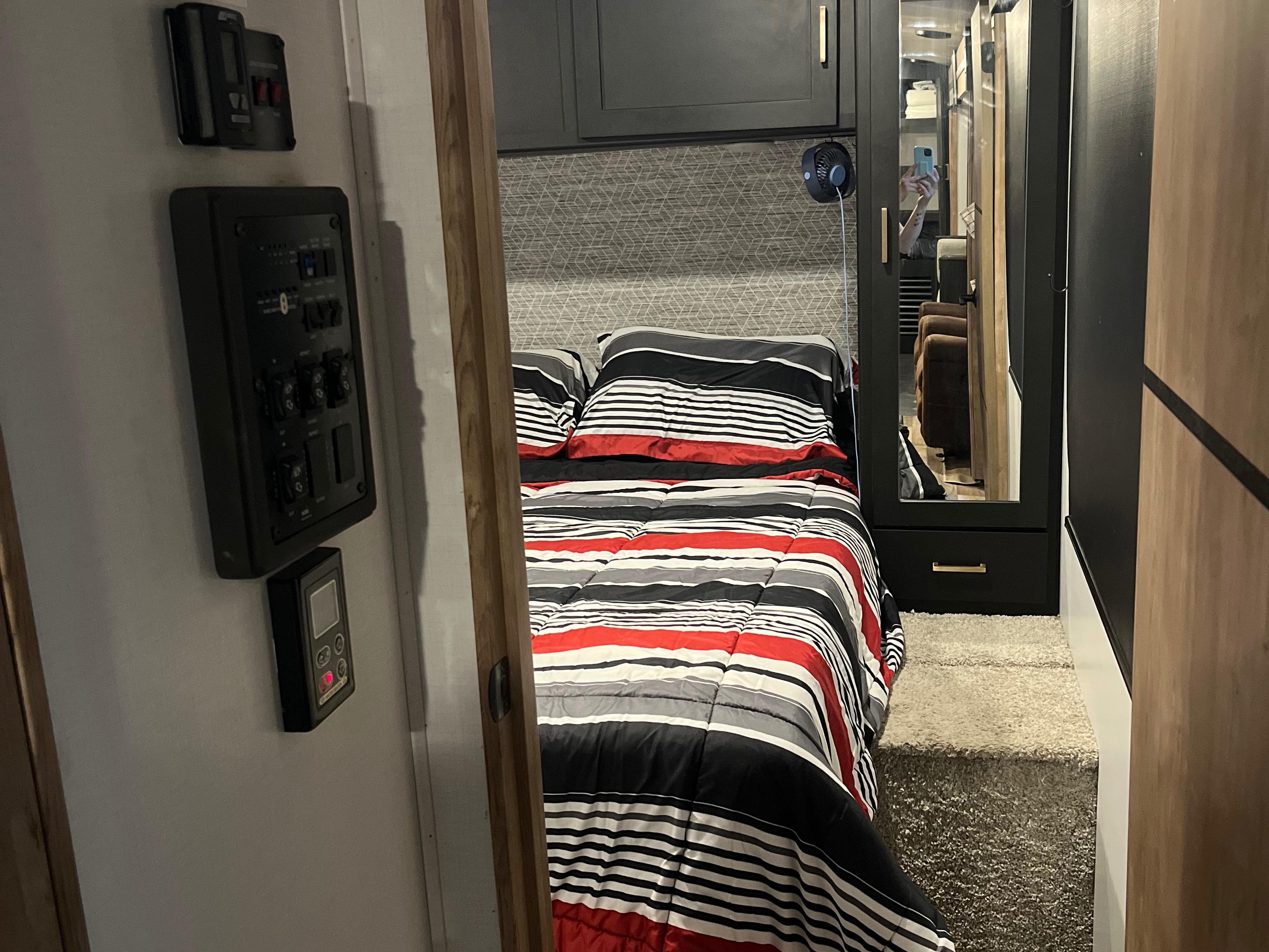 Cozy RV rental bedroom with striped bedding, control panels, and a mirrored wardrobe for comfortable travel.. Keystone RV Outback 2022
