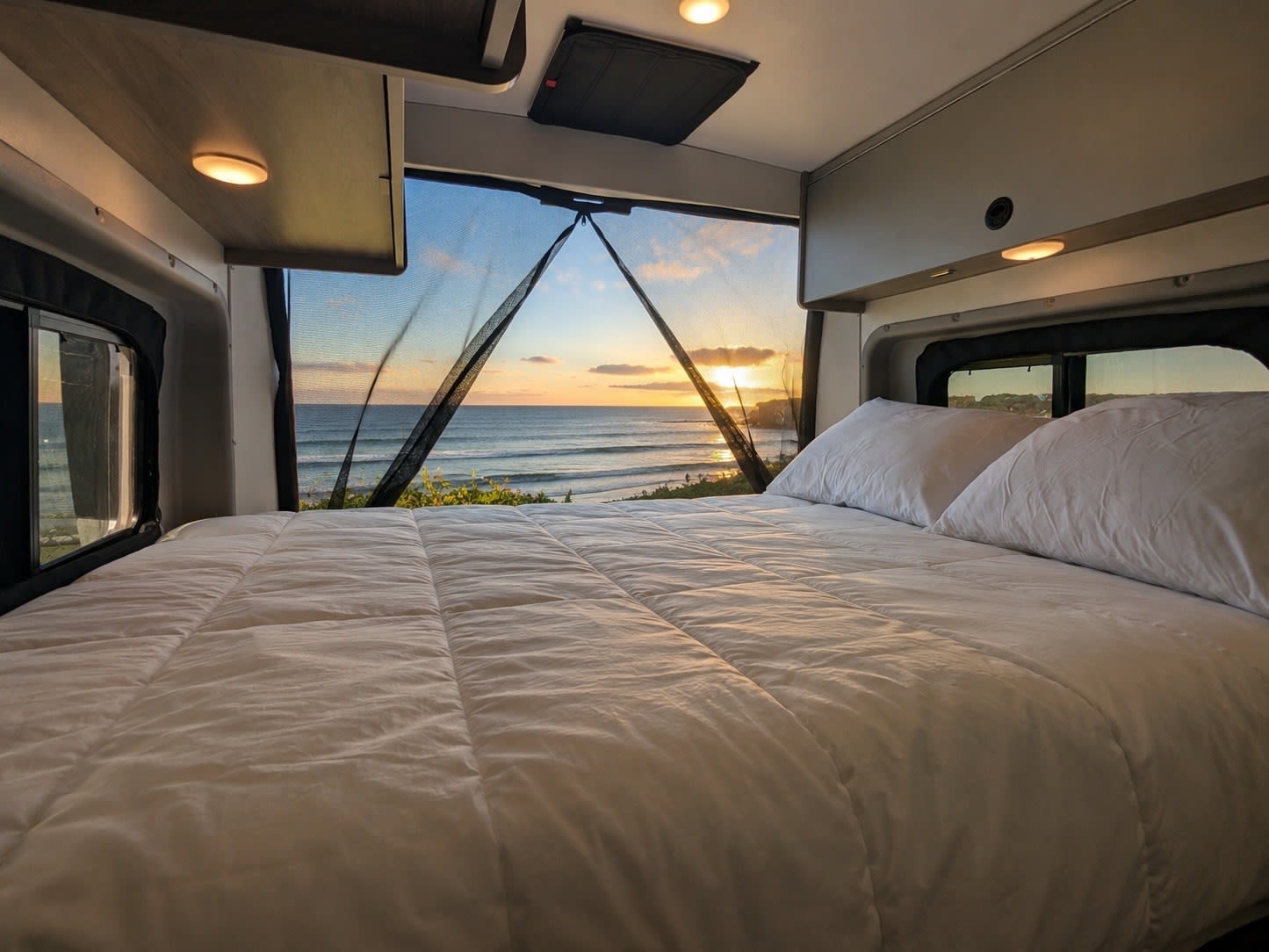 Experience breathtaking ocean sunset views from this cozy RV rental bedroom. Ideal for a serene travel experience.. Winnebago Solis 2021