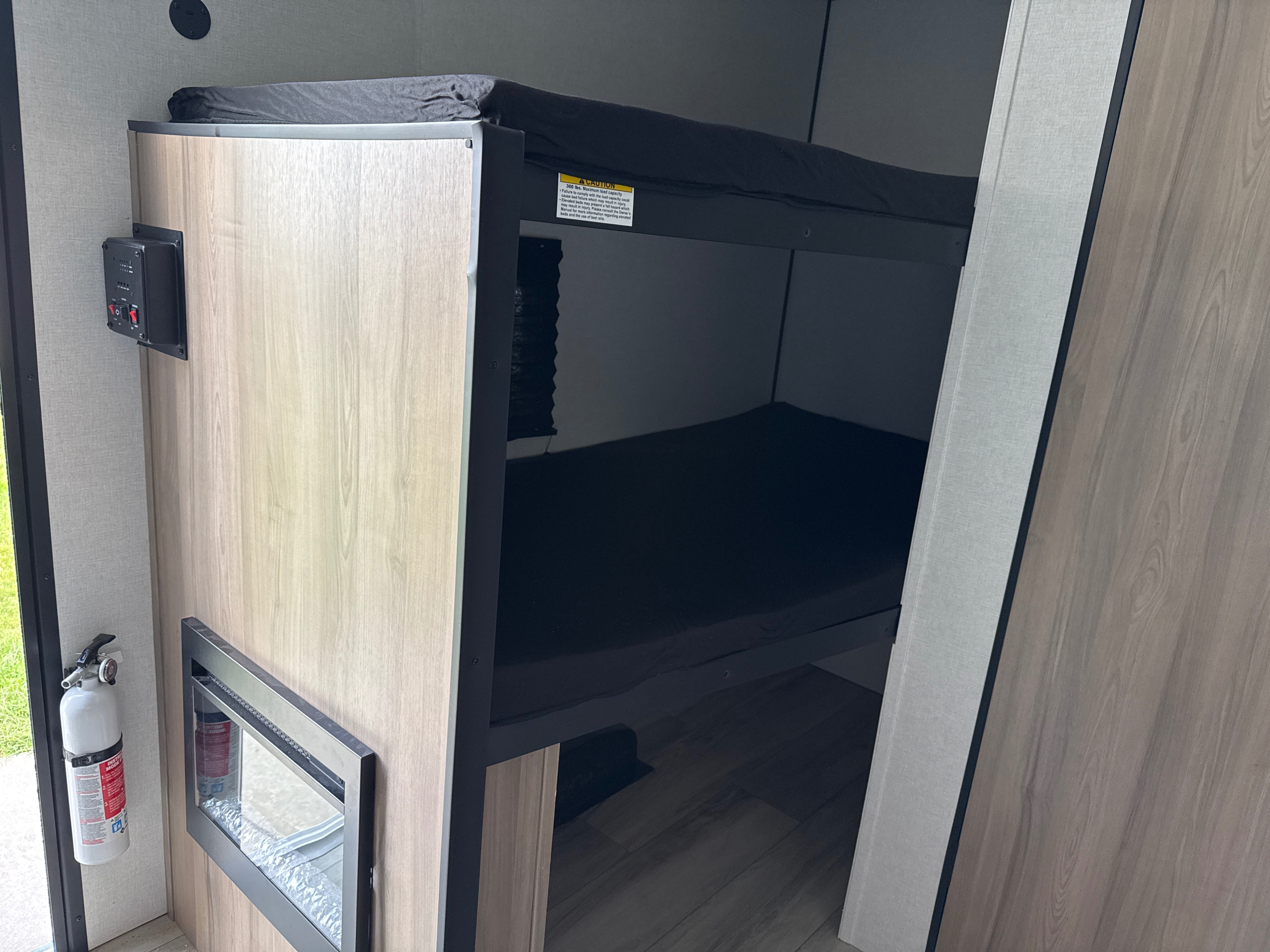 RV rental interior featuring cozy bunk beds, a control panel, fire extinguisher, and an electric heater for comfort.. Keystone RV Coleman 2026