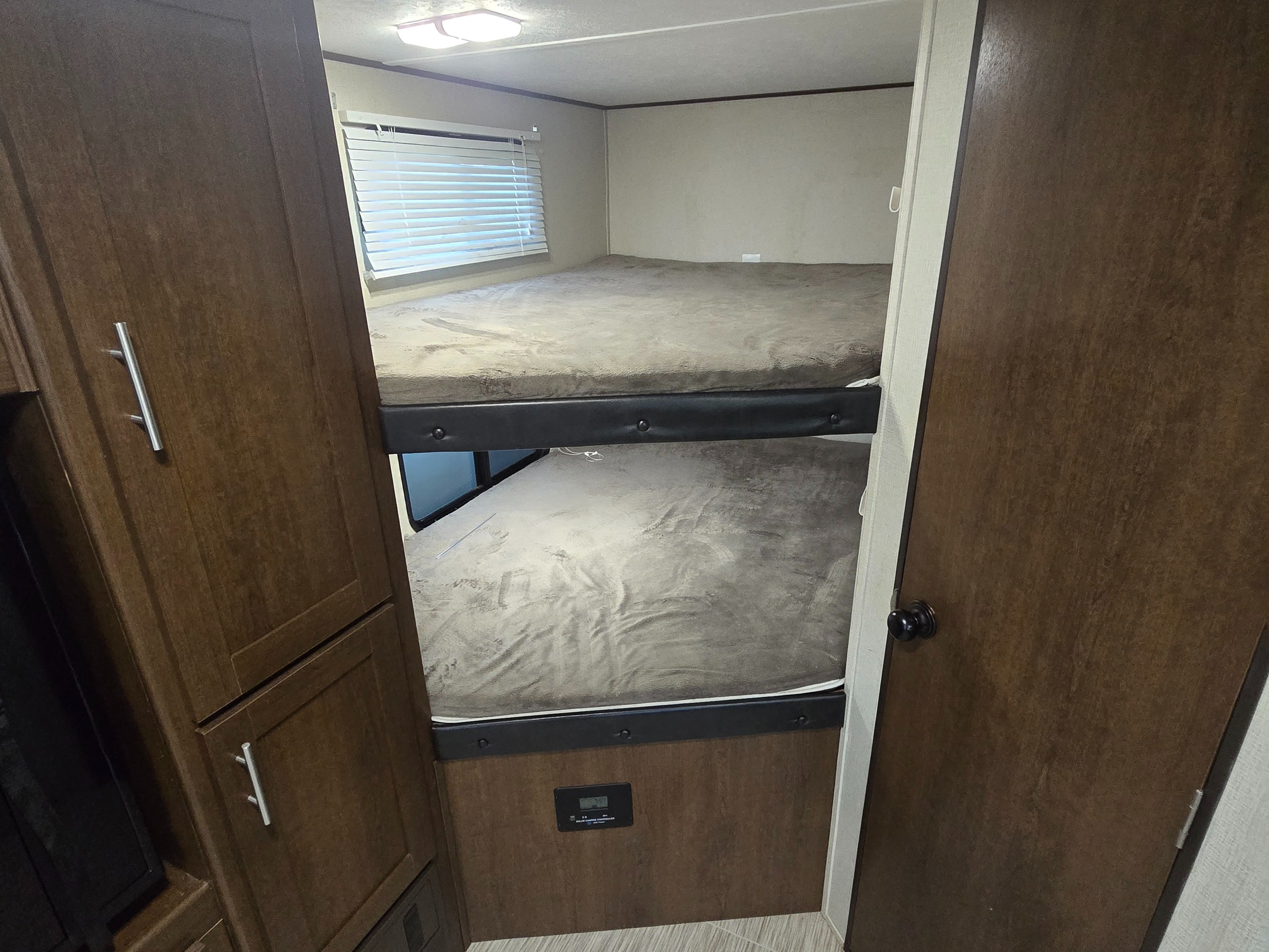 RV rental bunk beds: A cozy sleeping area with a window, wood cabinetry, and a control panel inside.. Avenger ATI 2018