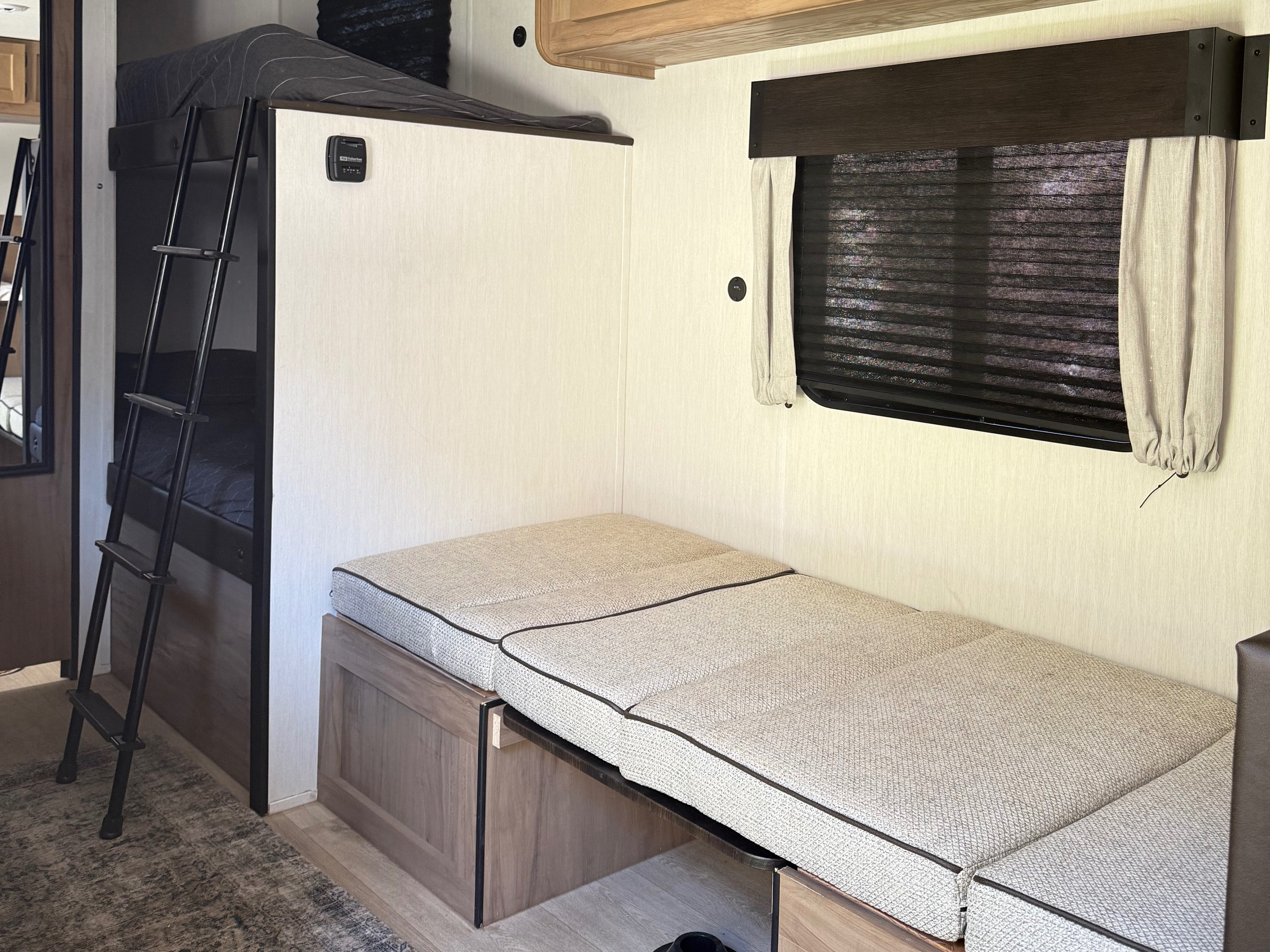RV rental: Interior shot highlighting bunk beds with ladder, a convertible dinette bench, & window with blinds.. Forest River Cherokee Wolf Pup 2025