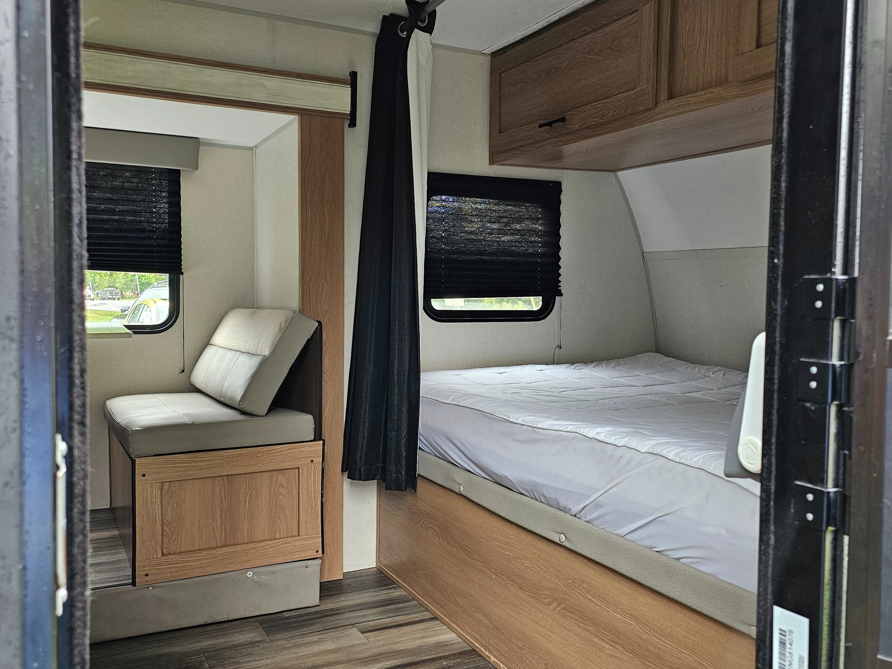 RV rental interior: A compact space with a bed on the right, a cushioned seat/dinette on the left, and overhead cabinets.. Avenger LT 2022