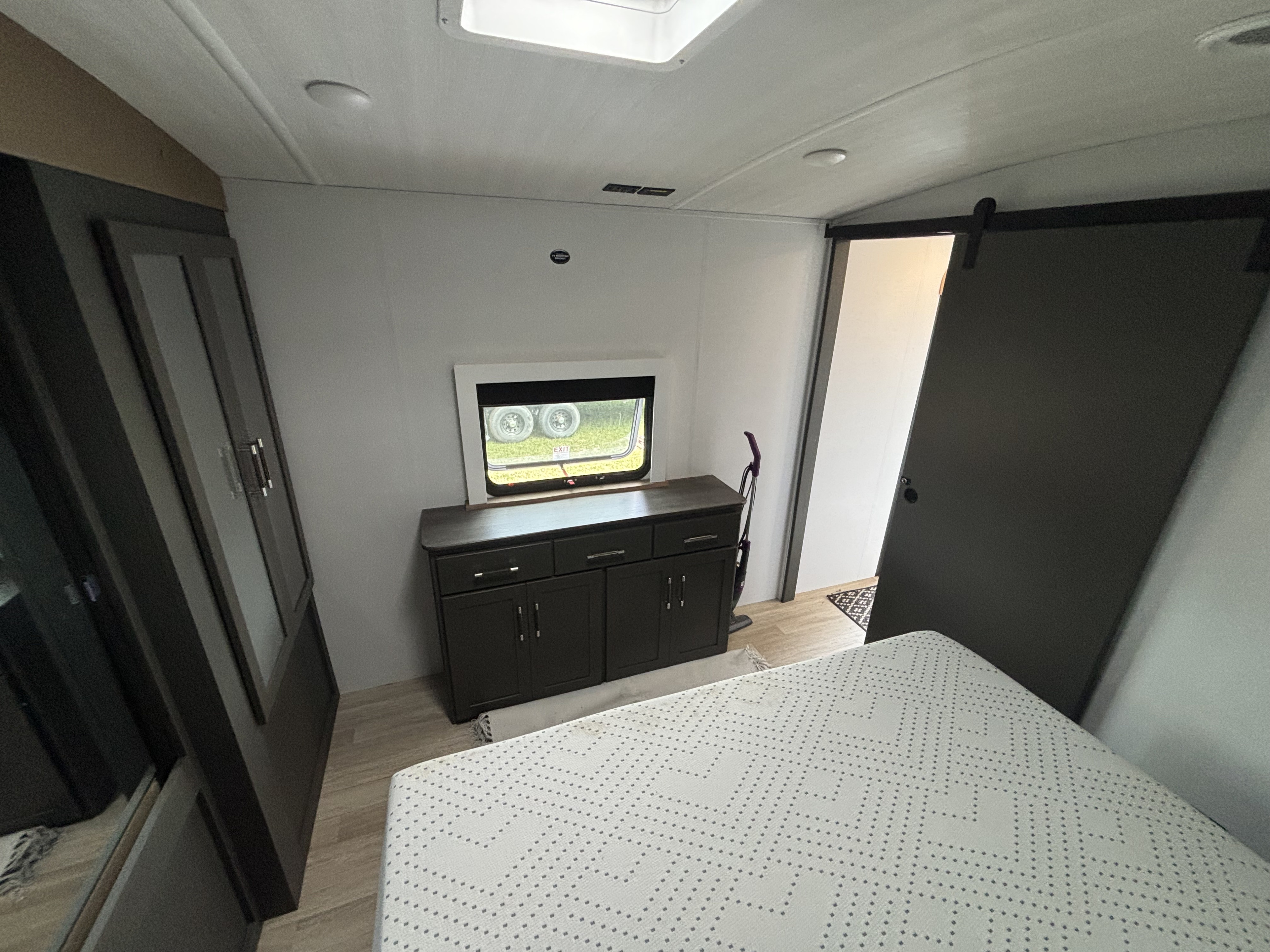 Experience comfort in this RV rental bedroom: large bed, dresser, storage, and stylish barn door. Ready for your travels!. Keystone RV Bullet Premium 2025