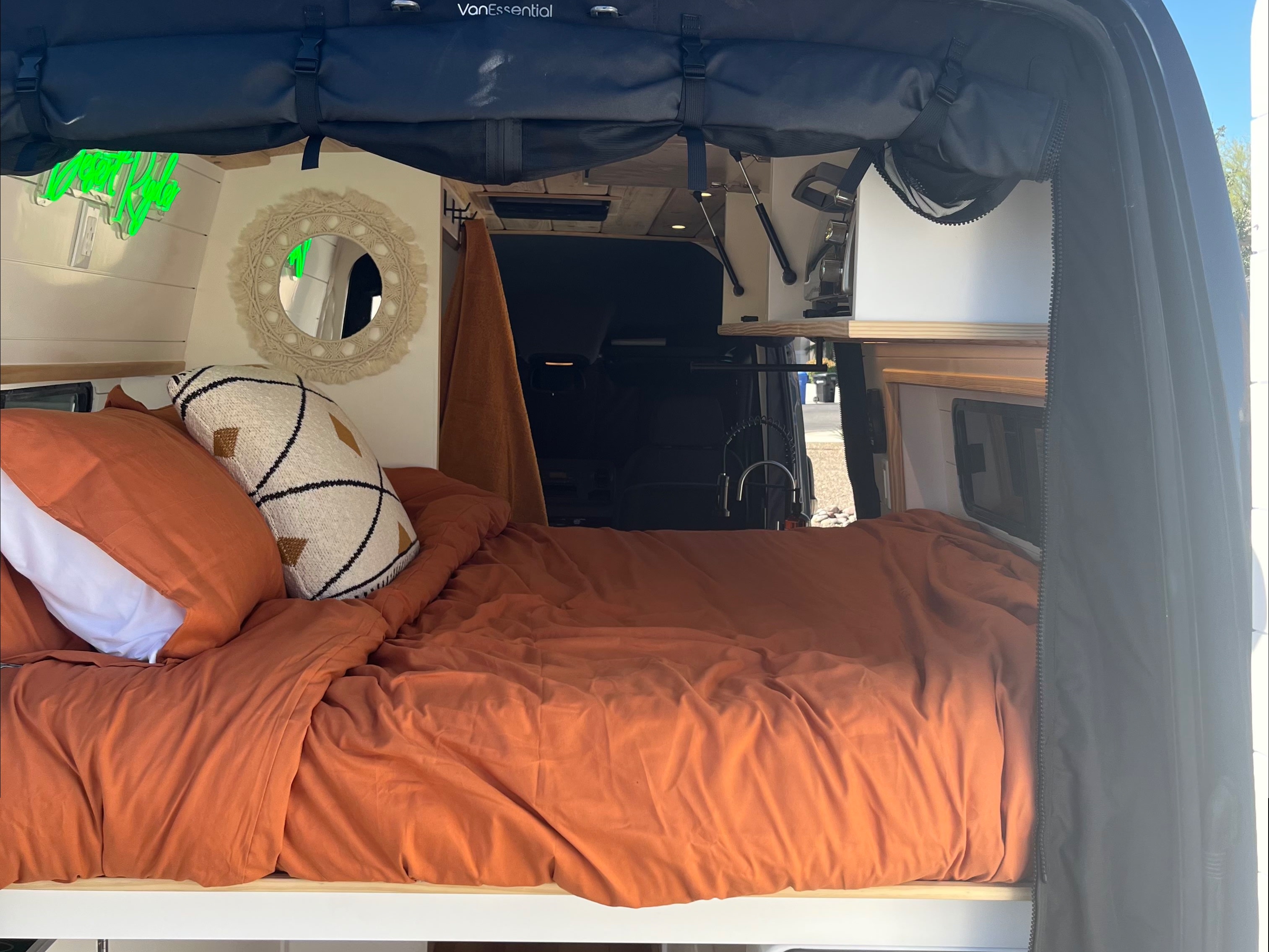 Cozy camper van interior for your next rv rental, featuring a bed, 'Happy Place' neon sign, and a compact kitchen faucet.. Mercedes Sprinter 2500 2019