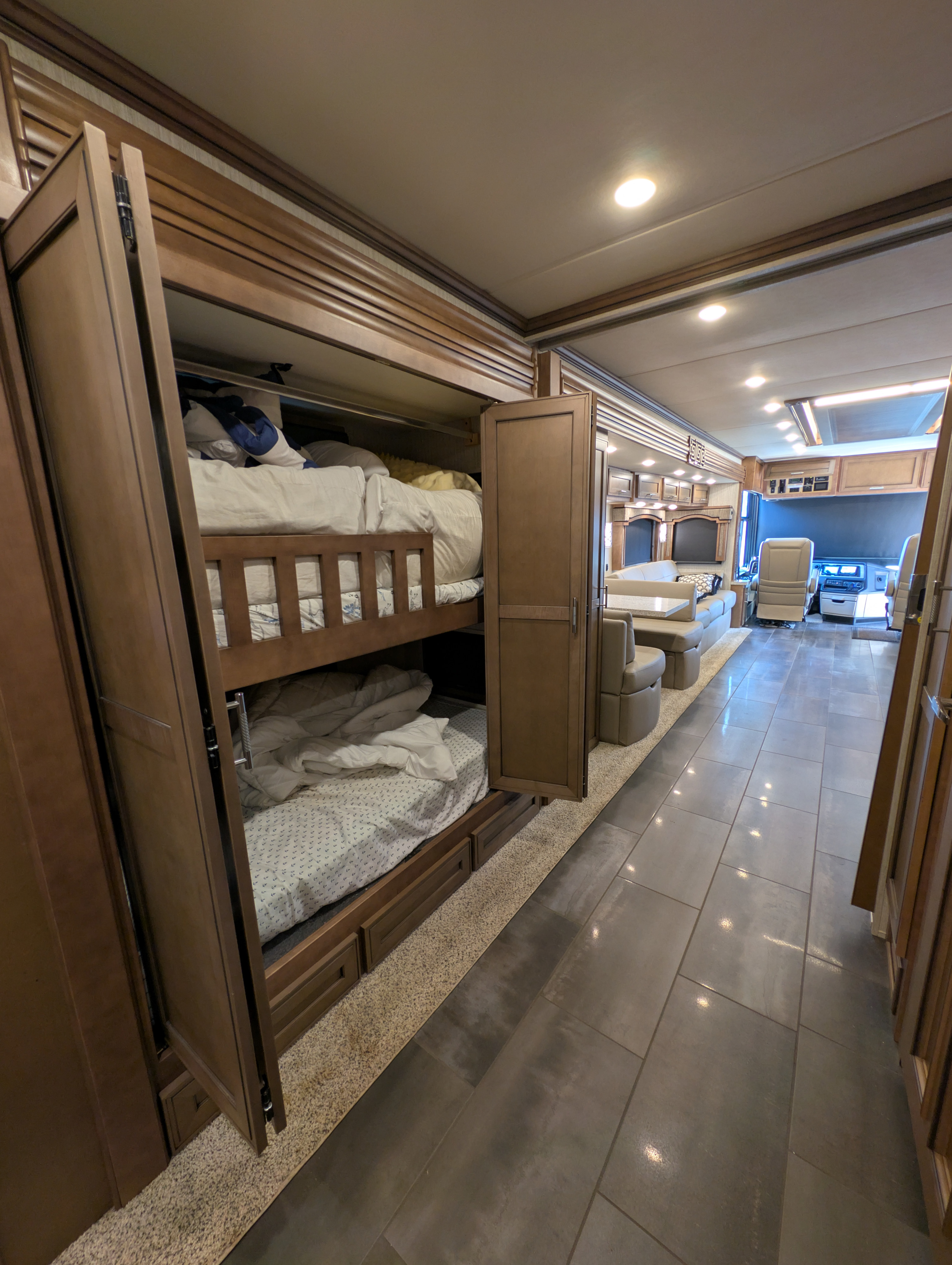 Spacious RV rental interior featuring bunk beds with privacy doors open, looking towards the living area and cockpit.. Ventana Ventana Motorhome 2020
