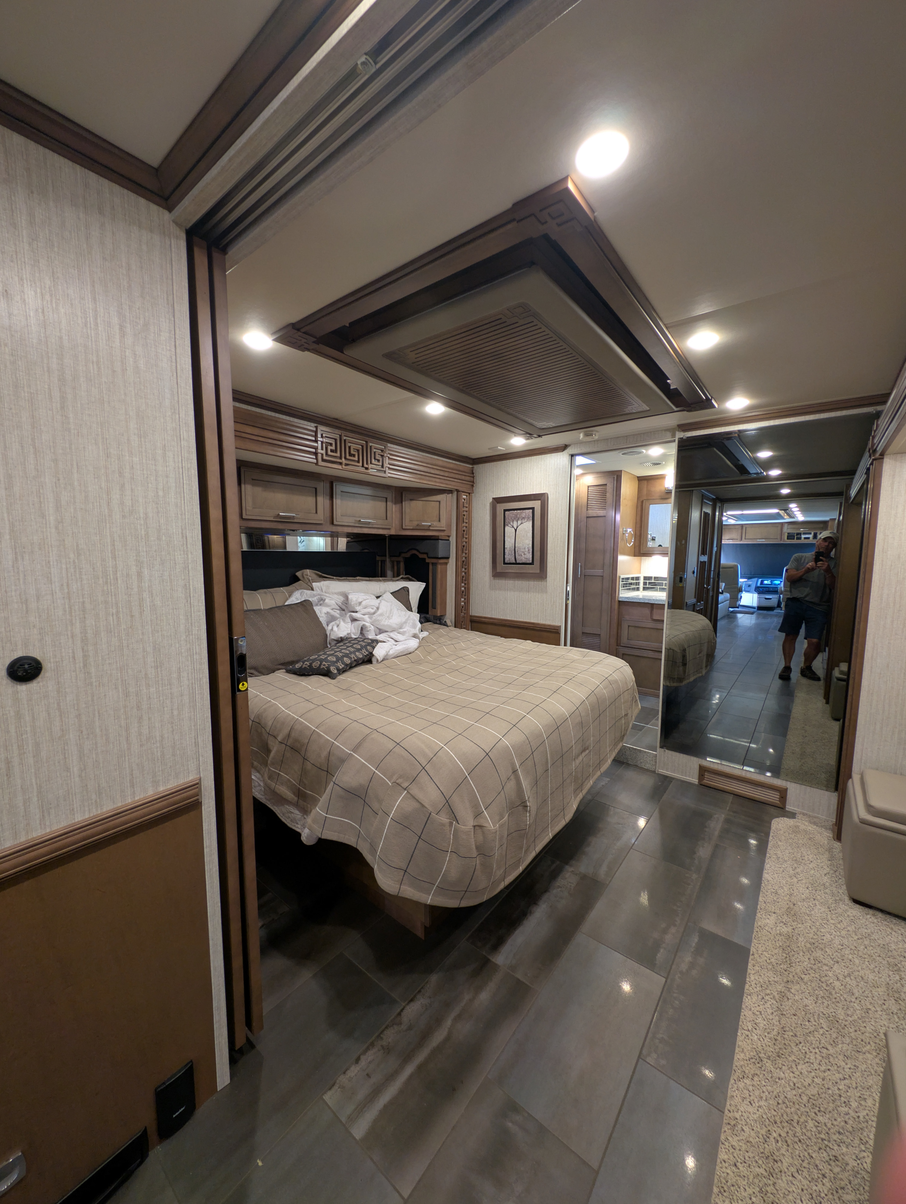 Luxurious RV rental bedroom featuring a comfy bed, rich wood accents, tiled floor, and mirrored closet. Ready for adventure.. Ventana Ventana Motorhome 2020