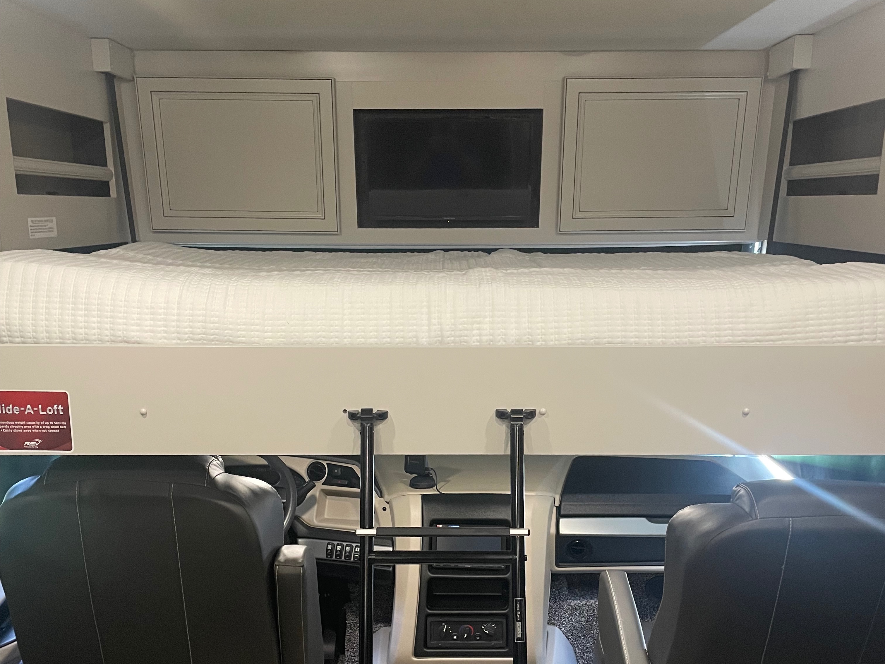 Spacious RV rental features a comfortable cab-over loft bed, overhead TV, cabinets, and ladder above the front seats.. Holiday Rambler Vacationer 2022