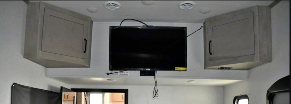 RV rental: Interior showing a wall-mounted TV, overhead storage cabinets, and ceiling vents for comfort.. Keystone RV Raptor Toy Hauler 2022