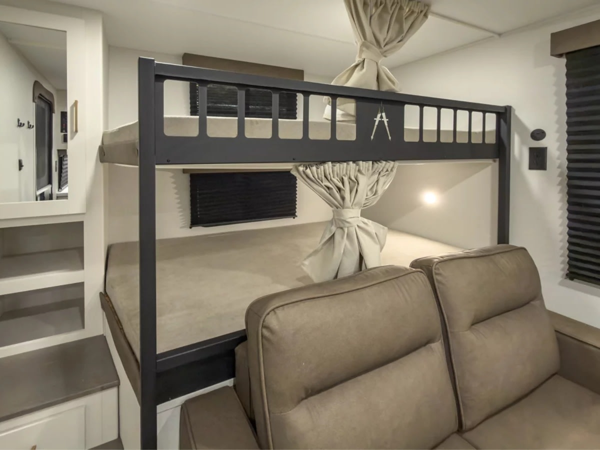 Cozy RV rental interior featuring bunk beds, a comfortable sofa, and built-in storage. Ideal for family travel.. Grand Design Transcend 2027