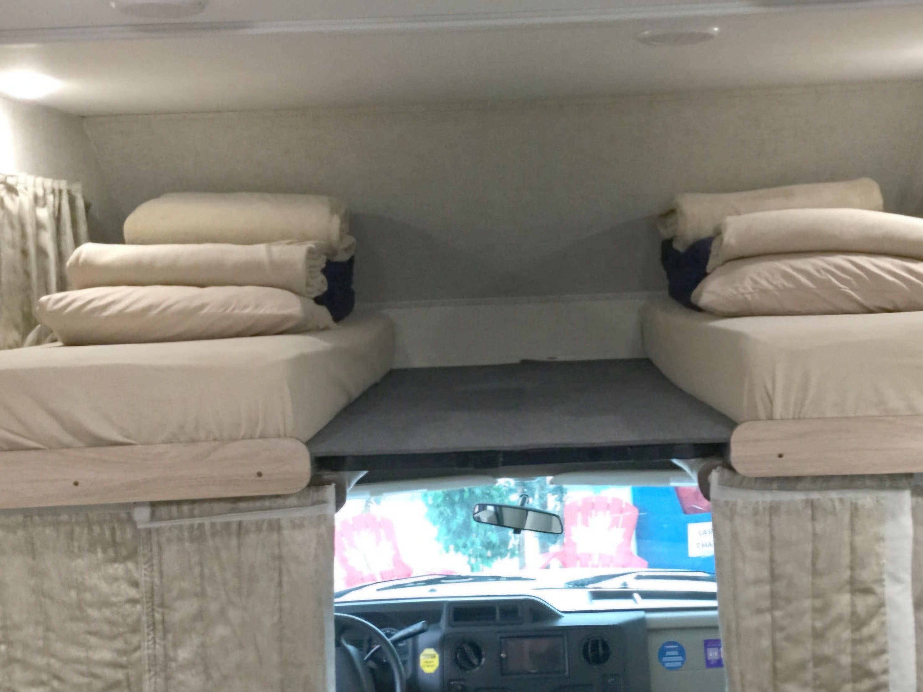 Interior view of an RV rental showing two comfortable cab-over beds with bedding, and the driver's cabin below.. Forest River SUNSEEKER 2650S CDW 2018