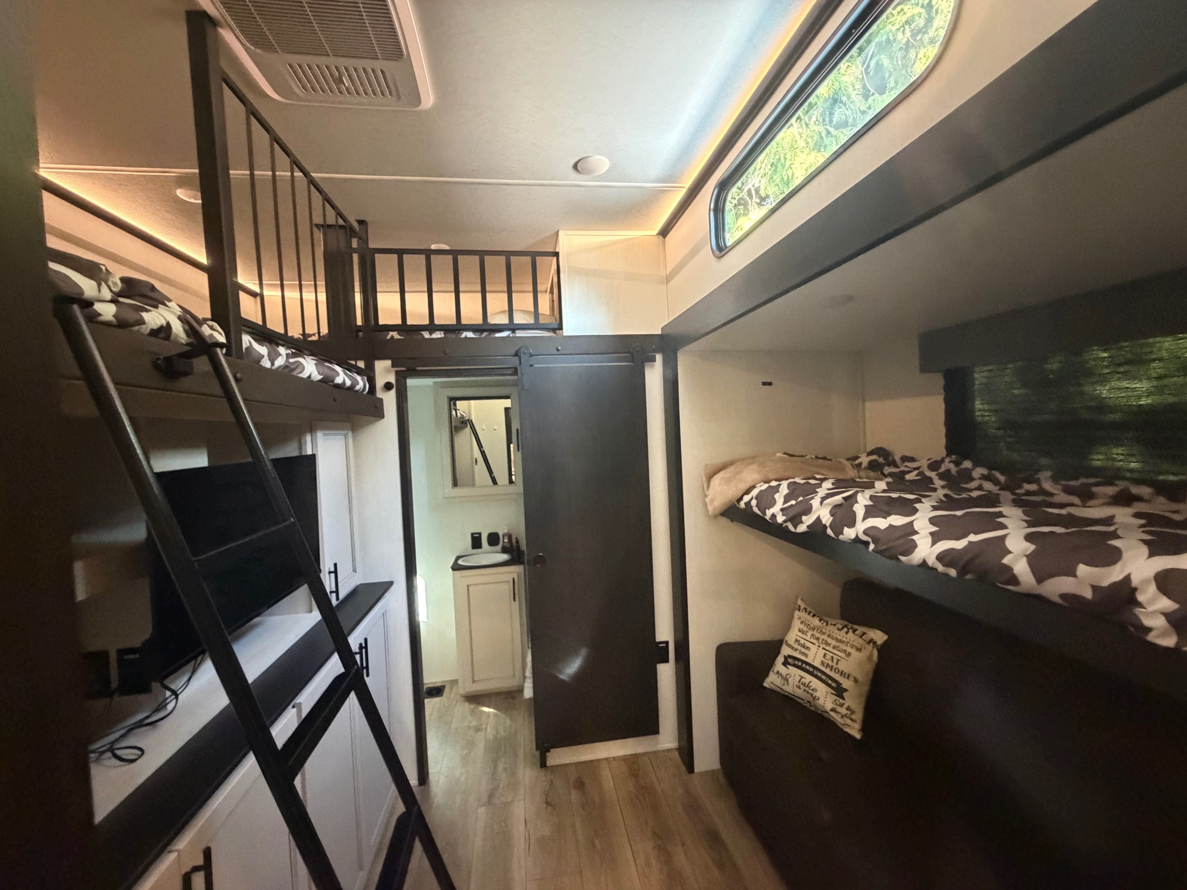 Cozy RV rental interior featuring multiple bunk beds, a loft, bathroom, and TV for a comfortable stay on the road.. Forest River Sabre 2025