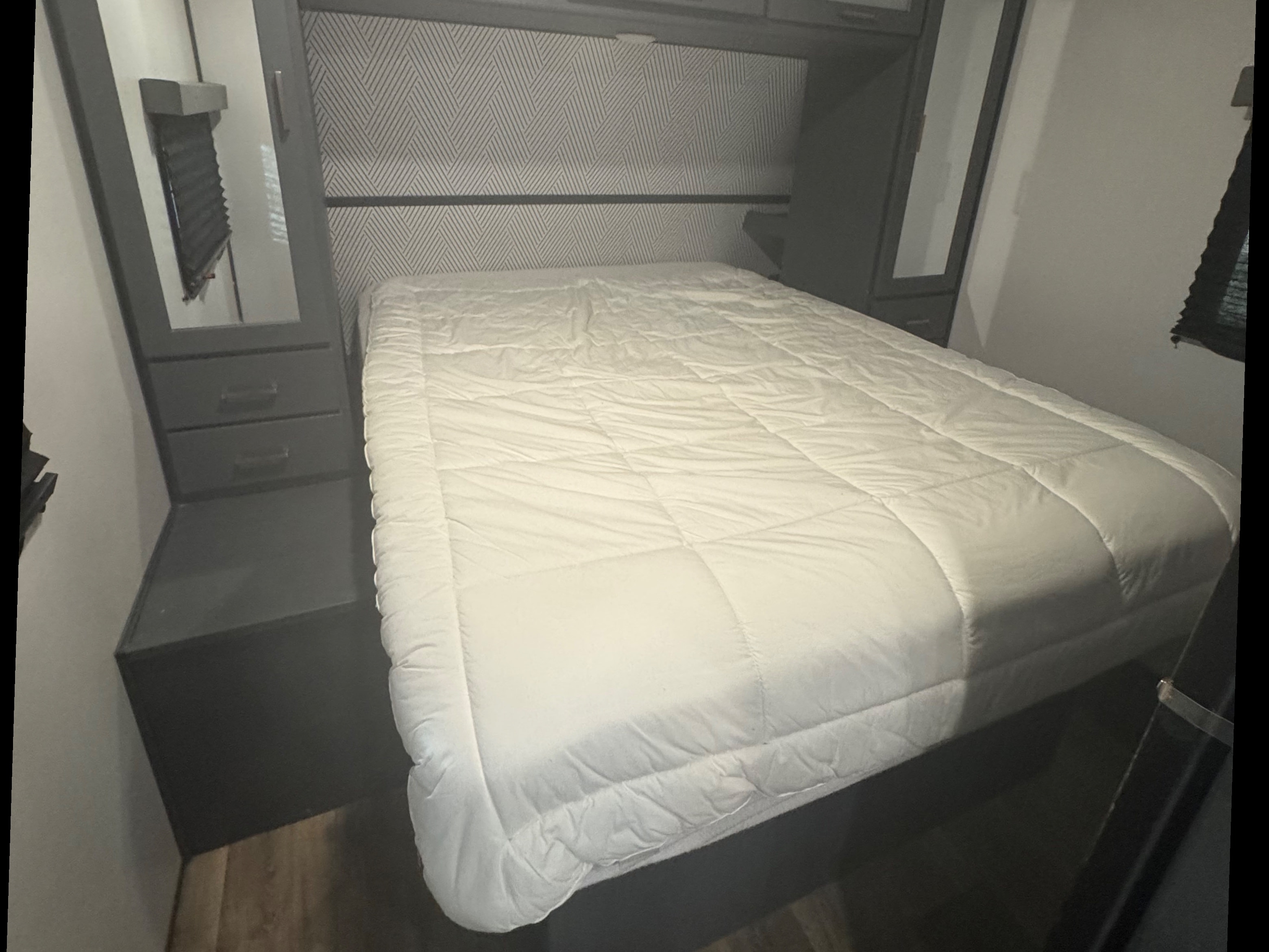 Cozy RV rental bedroom with a comfortable bed, geometric headboard, and overhead storage, perfect for your next adventure.. Keystone RV Bullet Ultra Lite 2022