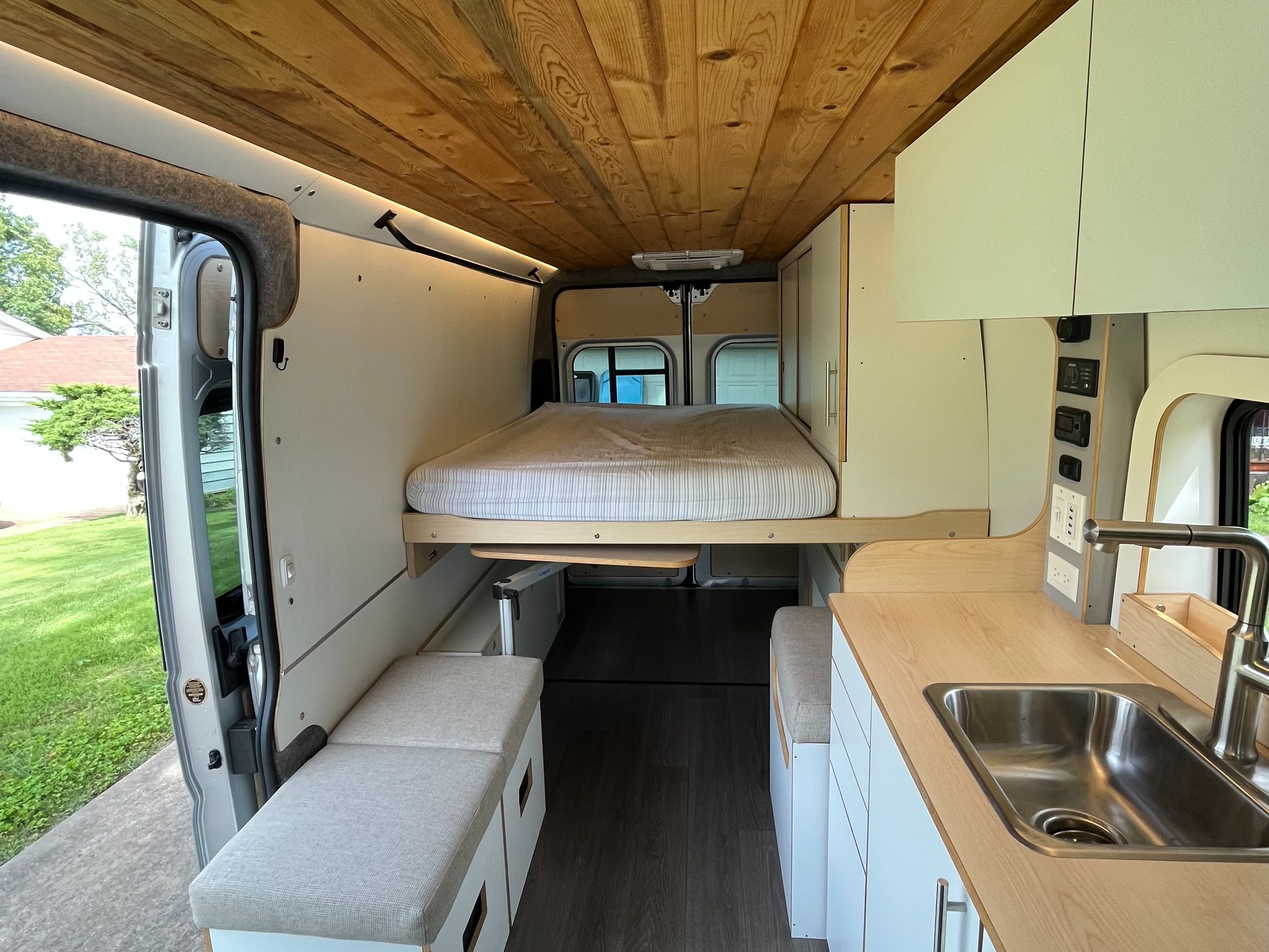This cozy RV rental features a camper van interior with a bed, kitchen sink, and bench seating, perfect for adventures.. Dave & Matt Vans Dave & Matt Vans Class B 2023