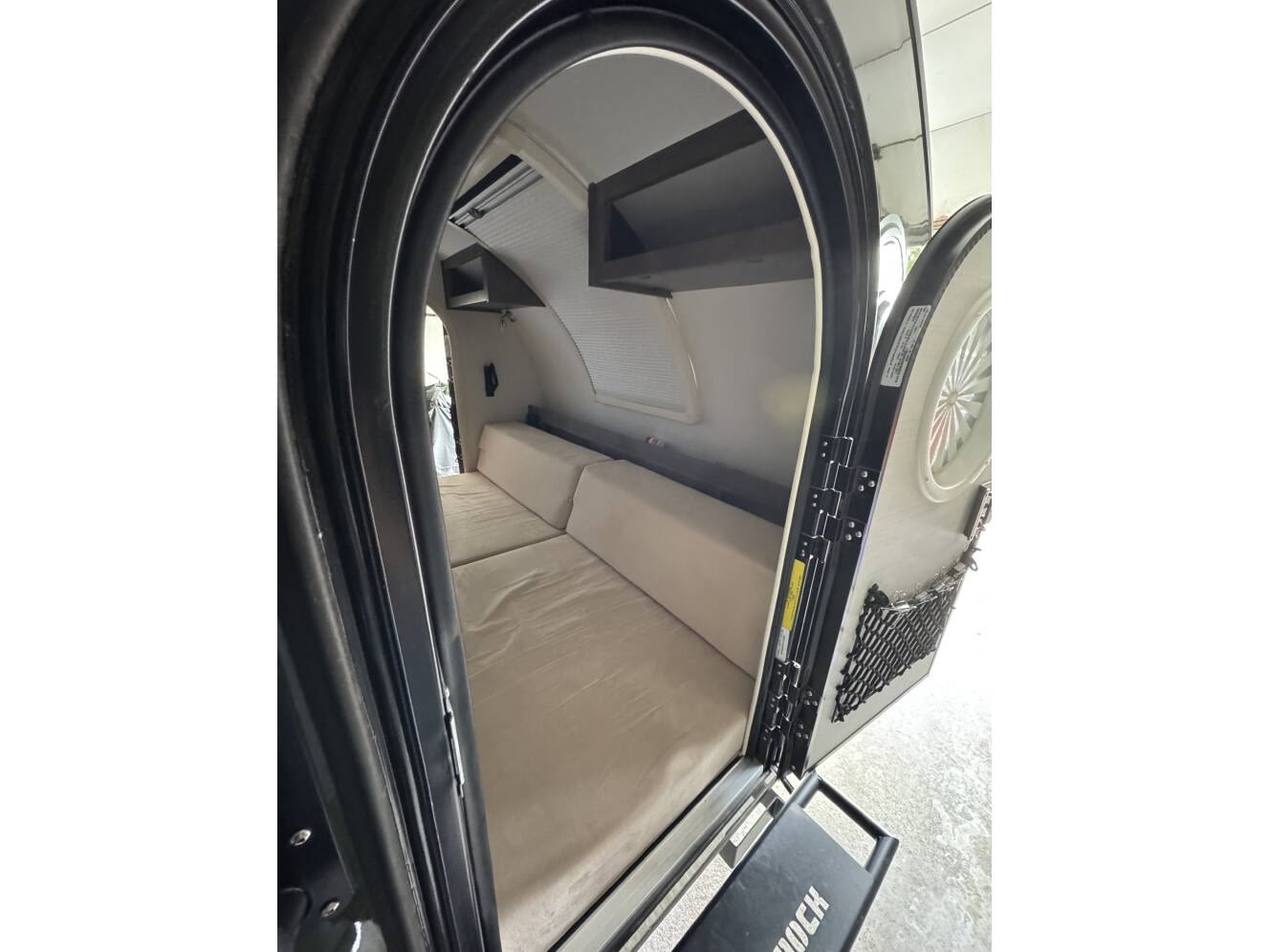 RV rental: Teardrop camper interior with a plush bed, storage shelves, and open door with step.. nuCamp T@G 2024