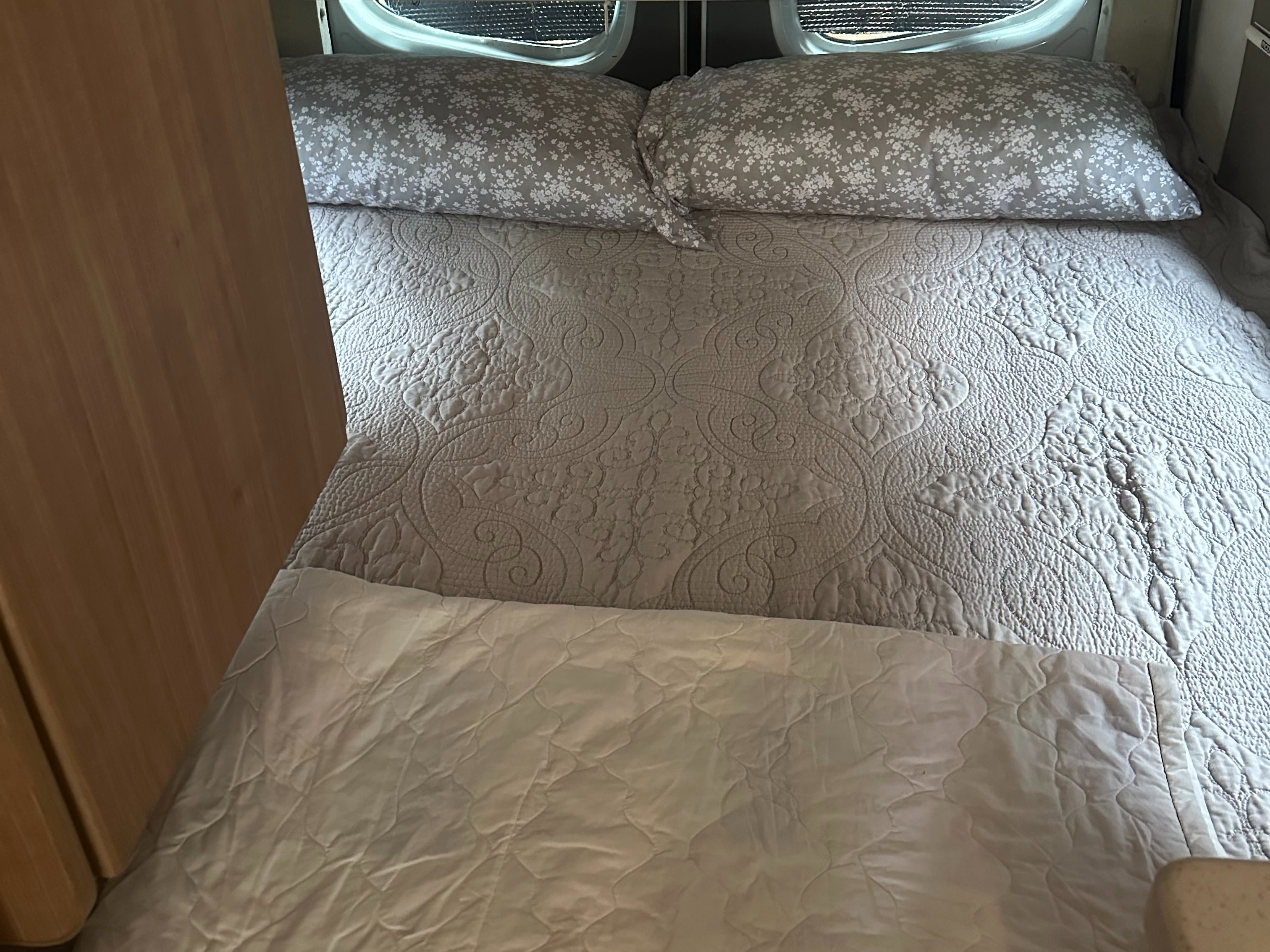 Made bed with patterned pillows & a quilted bedspread in a comfortable RV rental interior.. Winnebago Era 2013