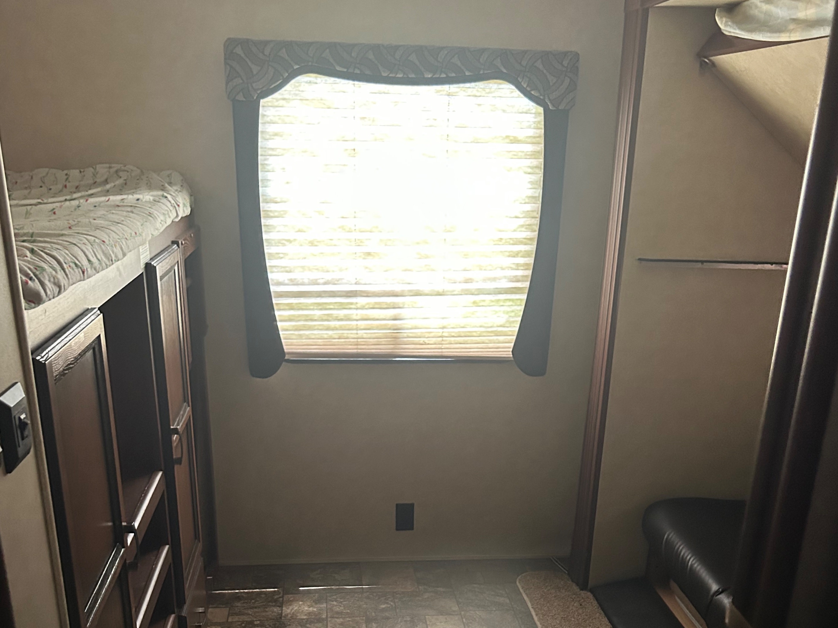 Cozy RV rental interior featuring bunk beds, a bright window with blinds, and comfortable seating—ideal for family adventures.. Crossroads RV Zinger 2012