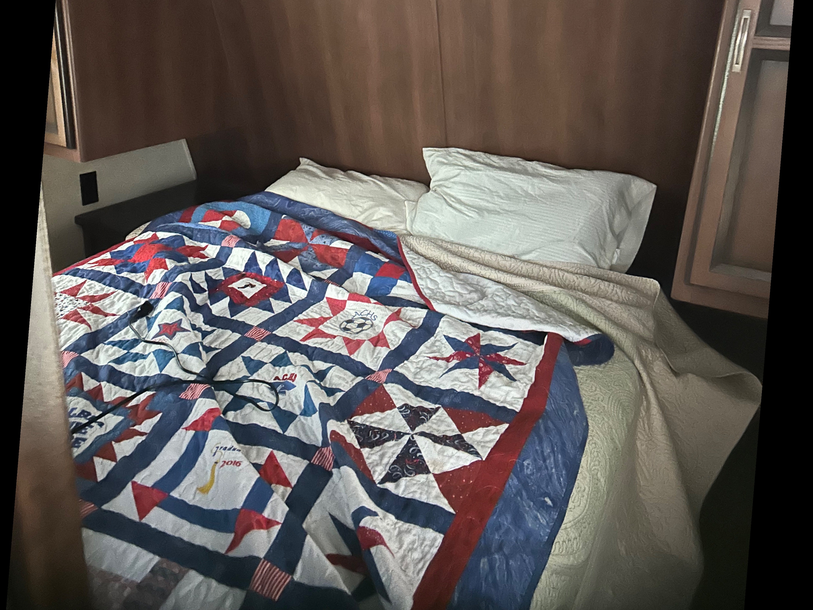 Cozy RV rental bedroom with a personalized patriotic quilt, possibly from a 2016 graduation. Ideal for travel.. Crossroads RV Zinger 2012