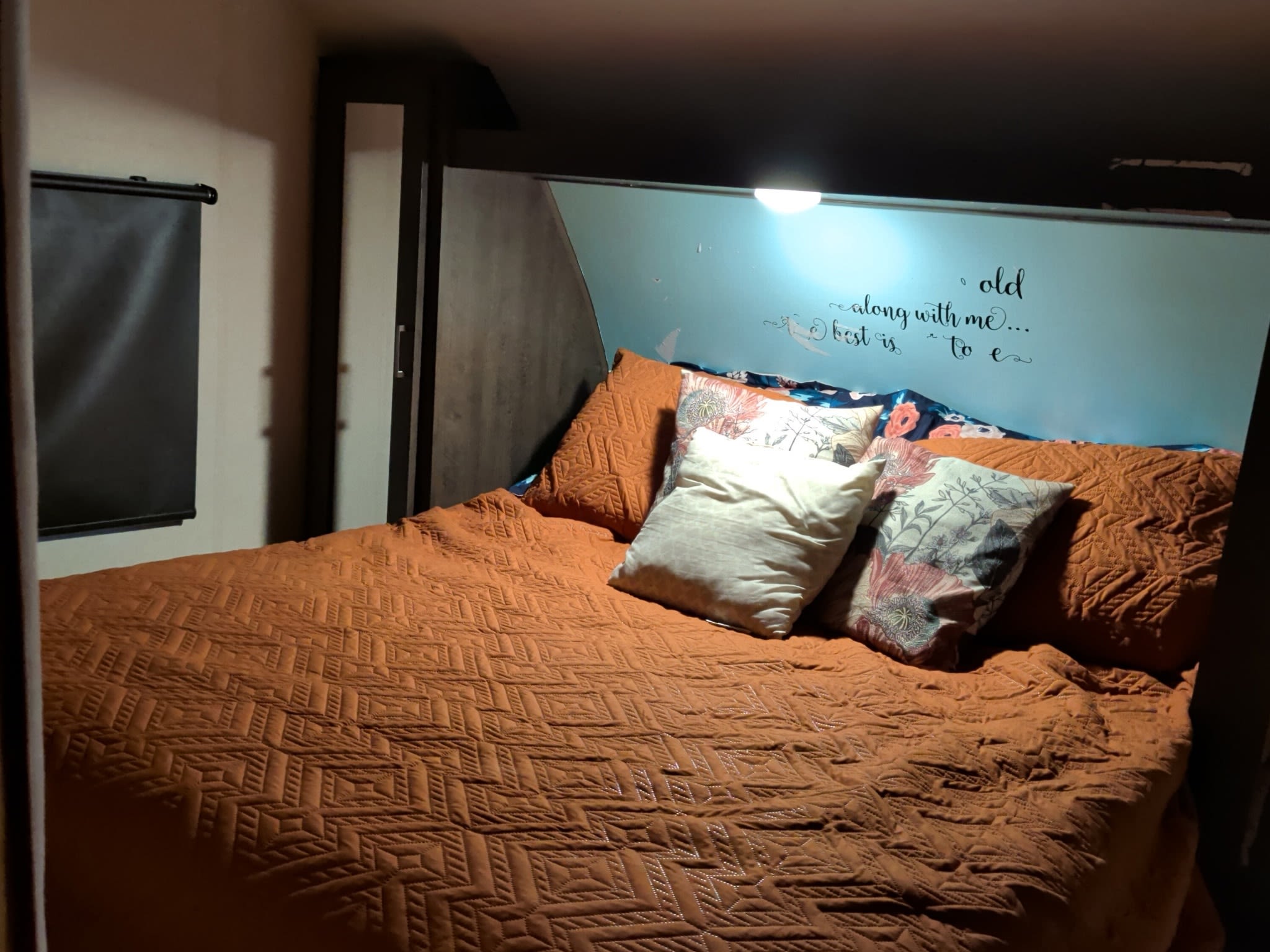 Cozy RV rental bedroom with an orange quilted bedspread, decorative pillows, and a light blue accent wall, perfect for travel.. Forest River Salem Cruise Lite 2018