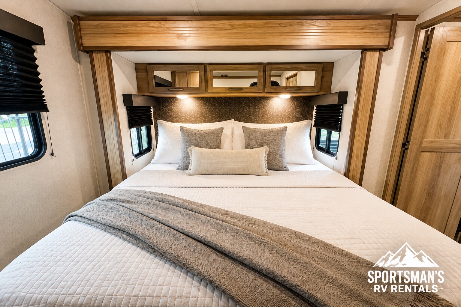 Cozy RV rental bedroom with a queen bed, plush pillows, overhead storage, and lighting. Perfect for your next adventure.. Keystone RV Outback 2025