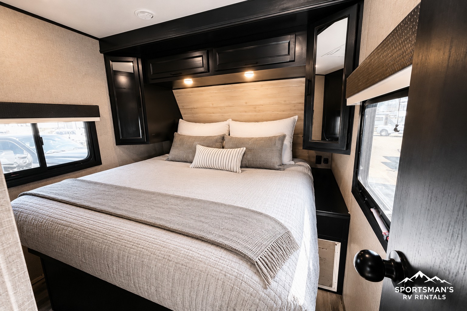 Cozy RV rental bedroom with a queen bed, stylish wooden headboard, overhead cabinets, and large windows.. Jayco Eagle 312 BHOK 2024