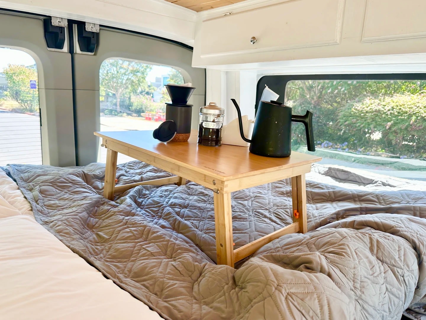 Cozy morning coffee with a pour-over setup and kettle on a bed tray inside an RV rental. Perfect for van life adventures.. Ford Transit 2018