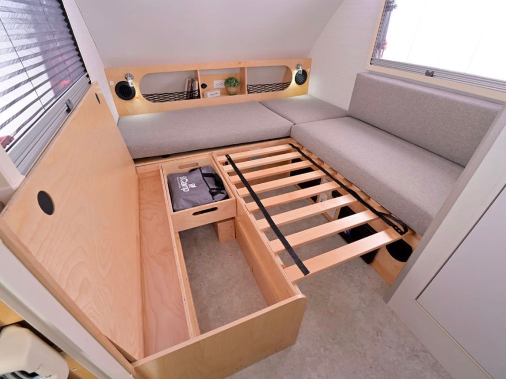 This RV rental interior features a convertible bed with slat base, under-bed storage, and overhead shelving in a compact camper.. nuCamp T@B 2026